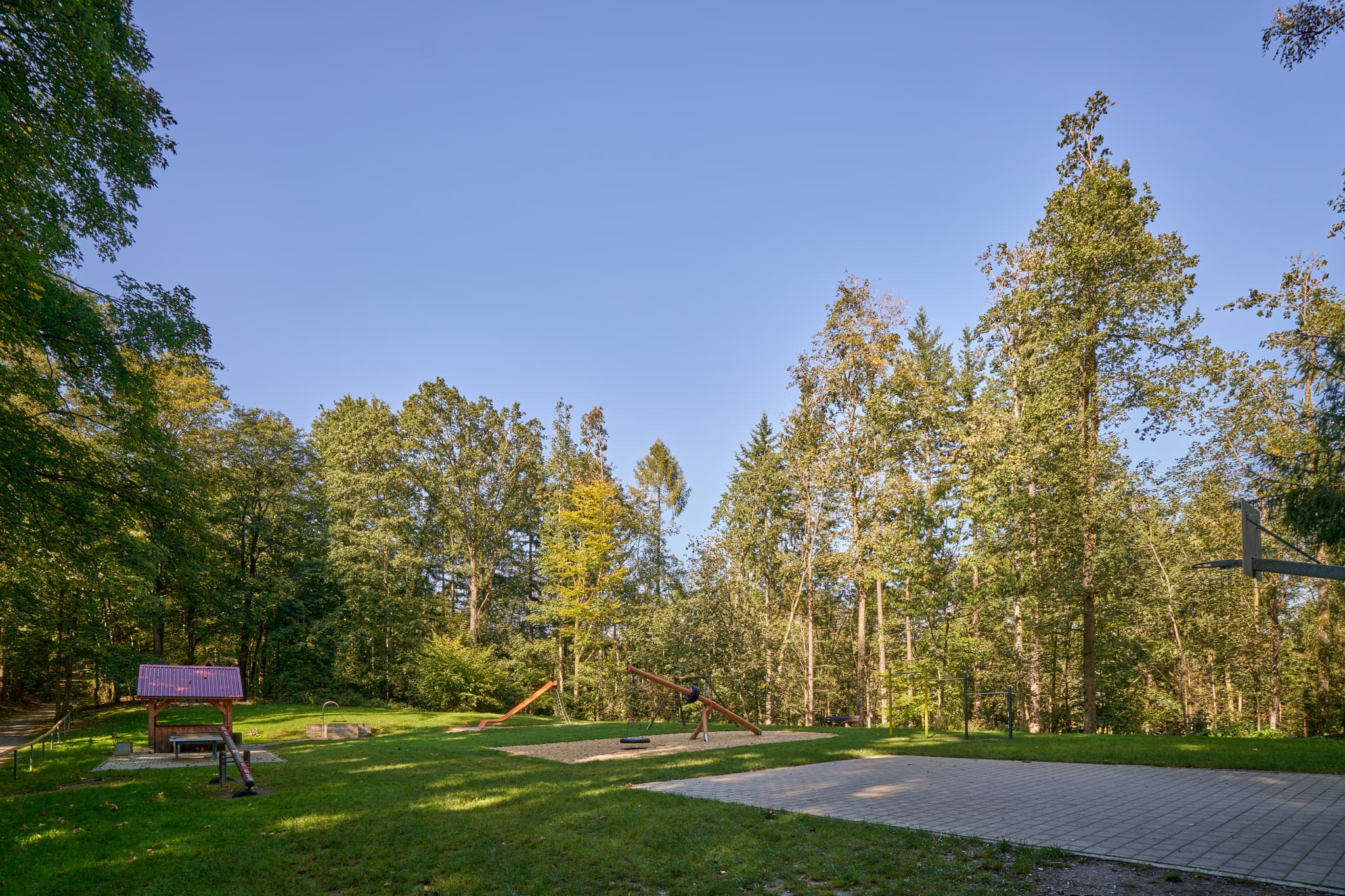 Spielplatz in Bad Griesbach, Passau, Niederbayern. Blick durch Holzkonstruktion auf Grünfläche mit Spielgeräten. Niederbayern, Bayern, Deutschland.