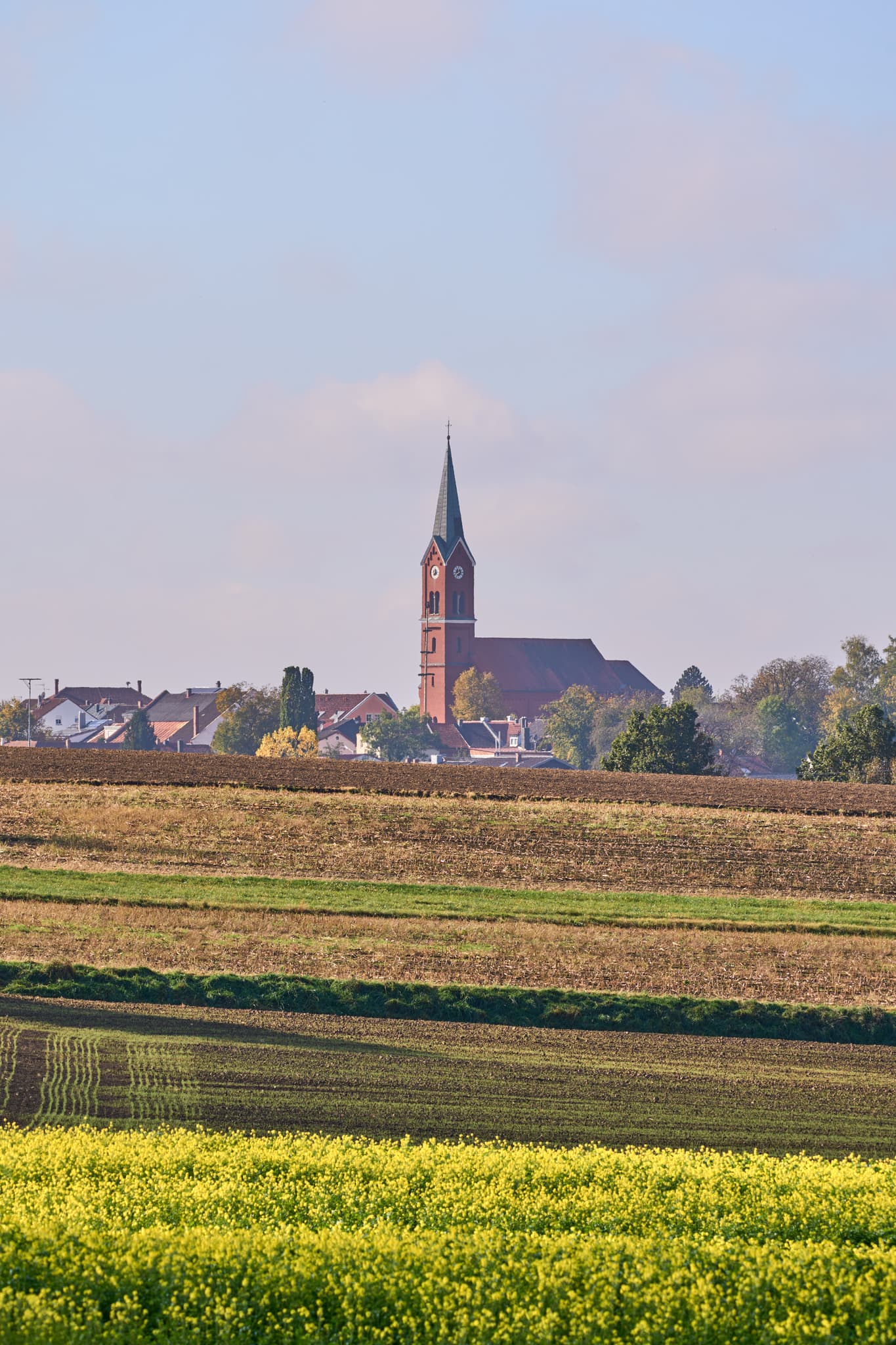 Ländliche Ortsansicht von Wurmannsquick, Rottal-Inn, Niederbayern, Deutschland. Zeigt die Pfarrkirche St. Andreas und Häuser mit Feldern im Holzland.