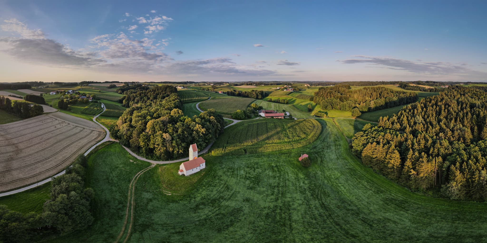 Landschaftsaufnahme von Feldern, Wald und einer kleinen Kirche in Sigrün bei Wald bei Winhöring, Pleiskirchen, Altötting, Oberbayern, Inn-Salzach, Deutschland.