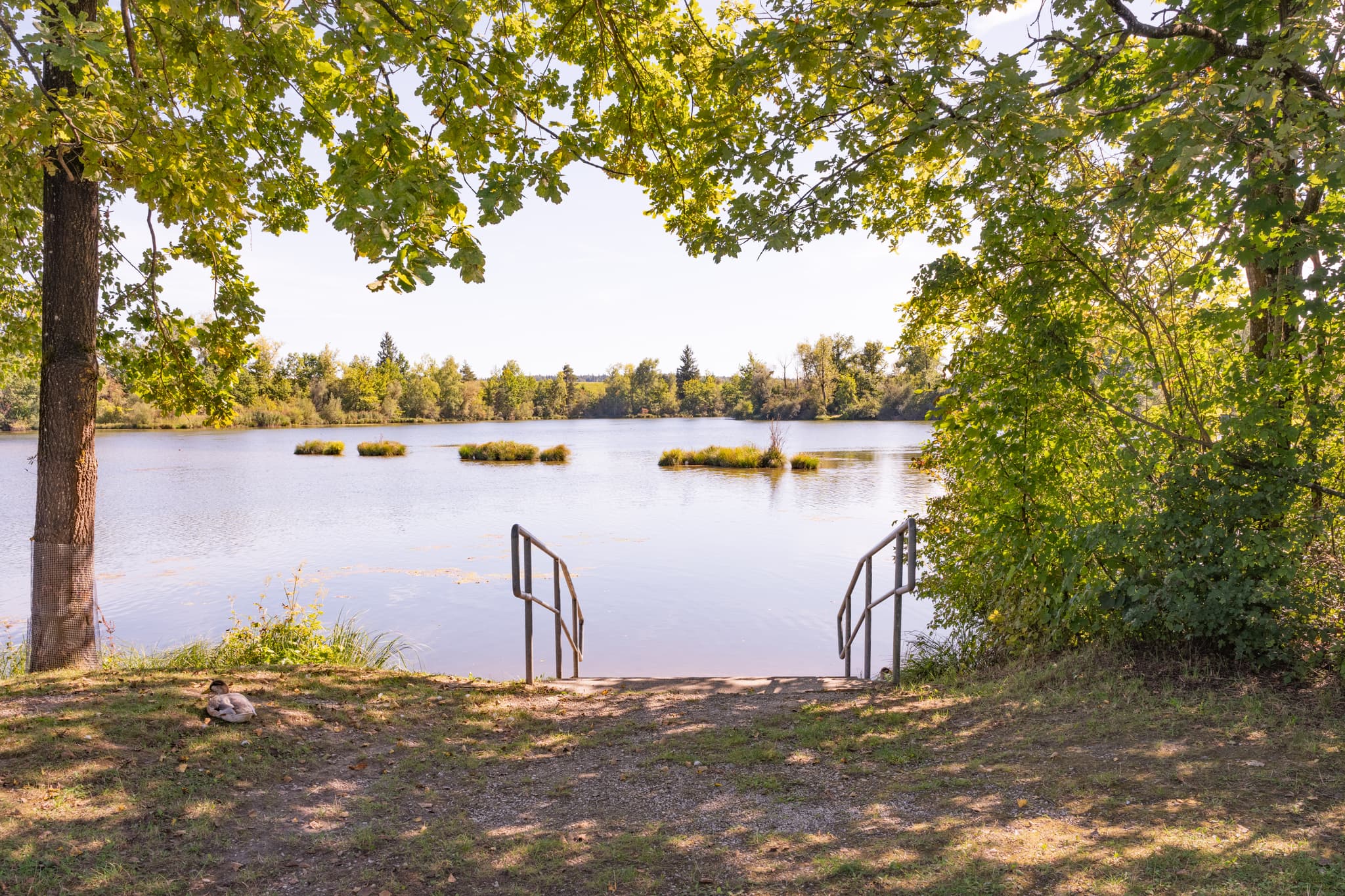 Badesee bei Kirchdorf am Inn im Landkreis Rottal-Inn, Niederbayern. Klare Gewässer mit Inseln, umgeben von Bäumen. Naherholung im Bäderdreieck, Deutschland.