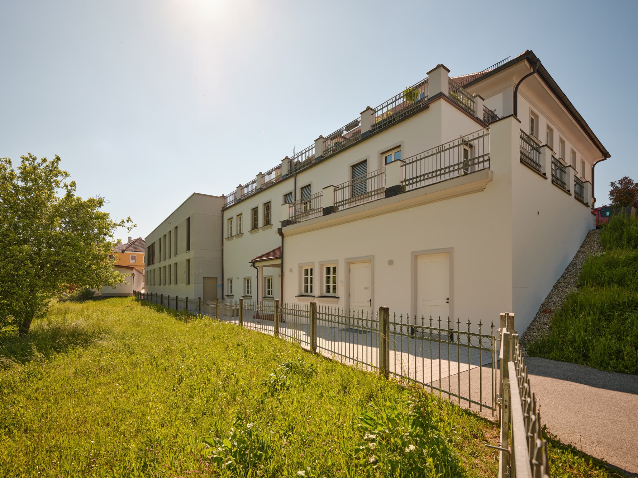 Rückgebäude der Gemeinde Reischach, Landkreis Altötting, Oberbayern, Deutschland. Zaun und Weg zwischen Reischachbach und Gemeinde.