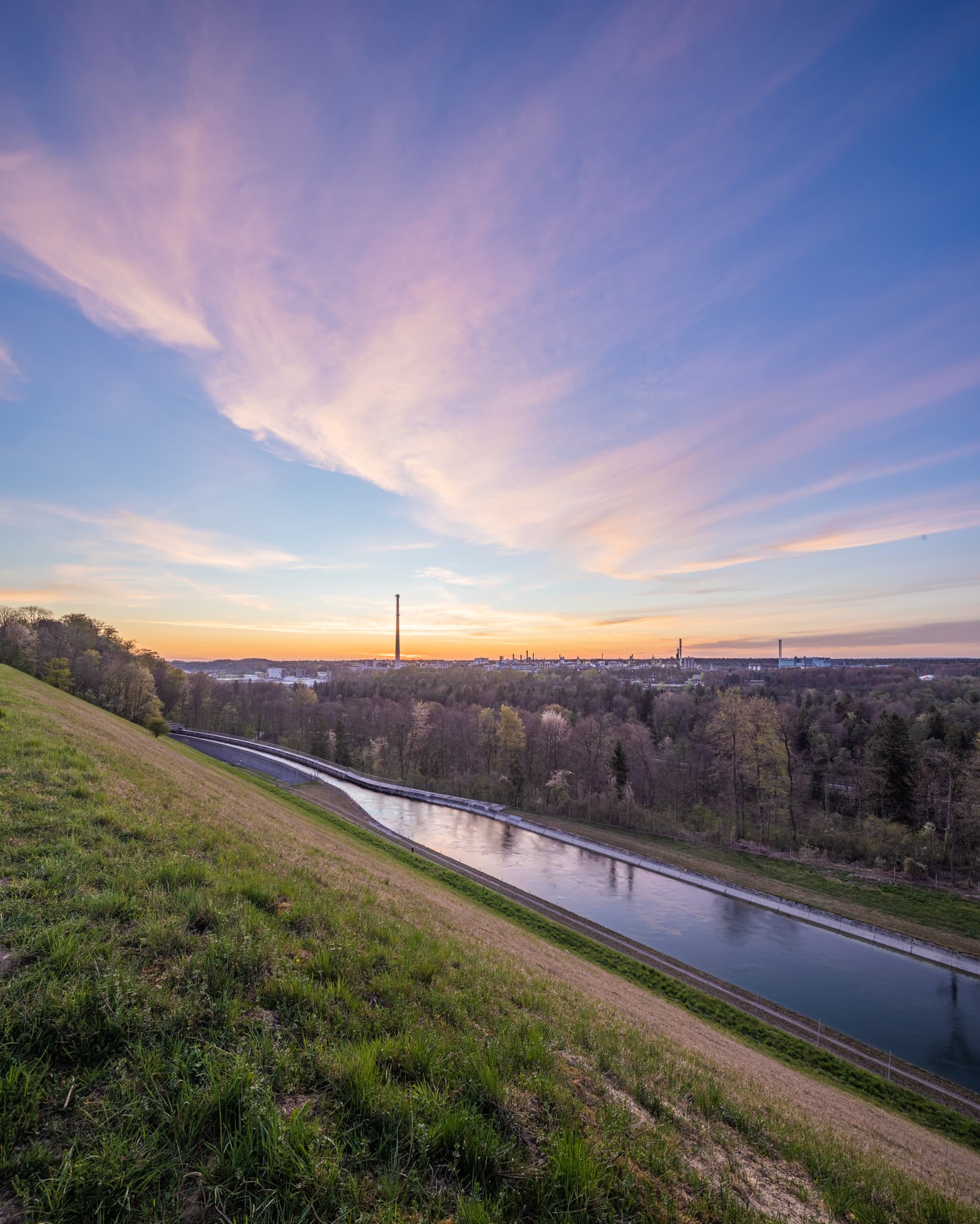 Alzkanal und Werk Gendorf in Burgkirchen, Altötting, Oberbayern, Inn-Salzach. Kanal, Grashang, Wald, Industriegebäude im Abendlicht.