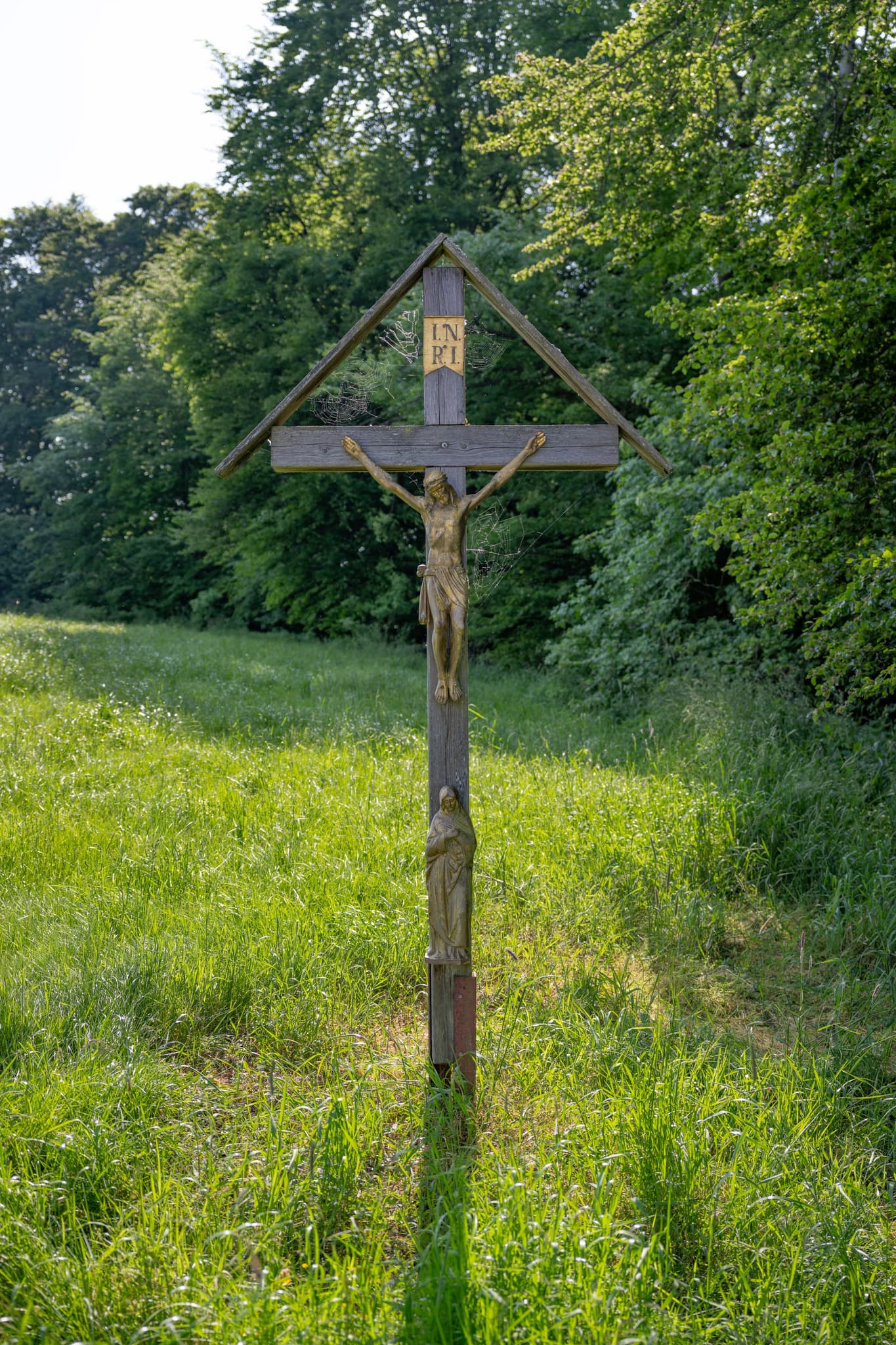 Wegkreuz aam Waldrand bei Friesing, Reischach, Altötting, Oberbayern. Ländliche Region Inn-Salzach. Das Kruzifix ist kunstvoll geschnitzt.