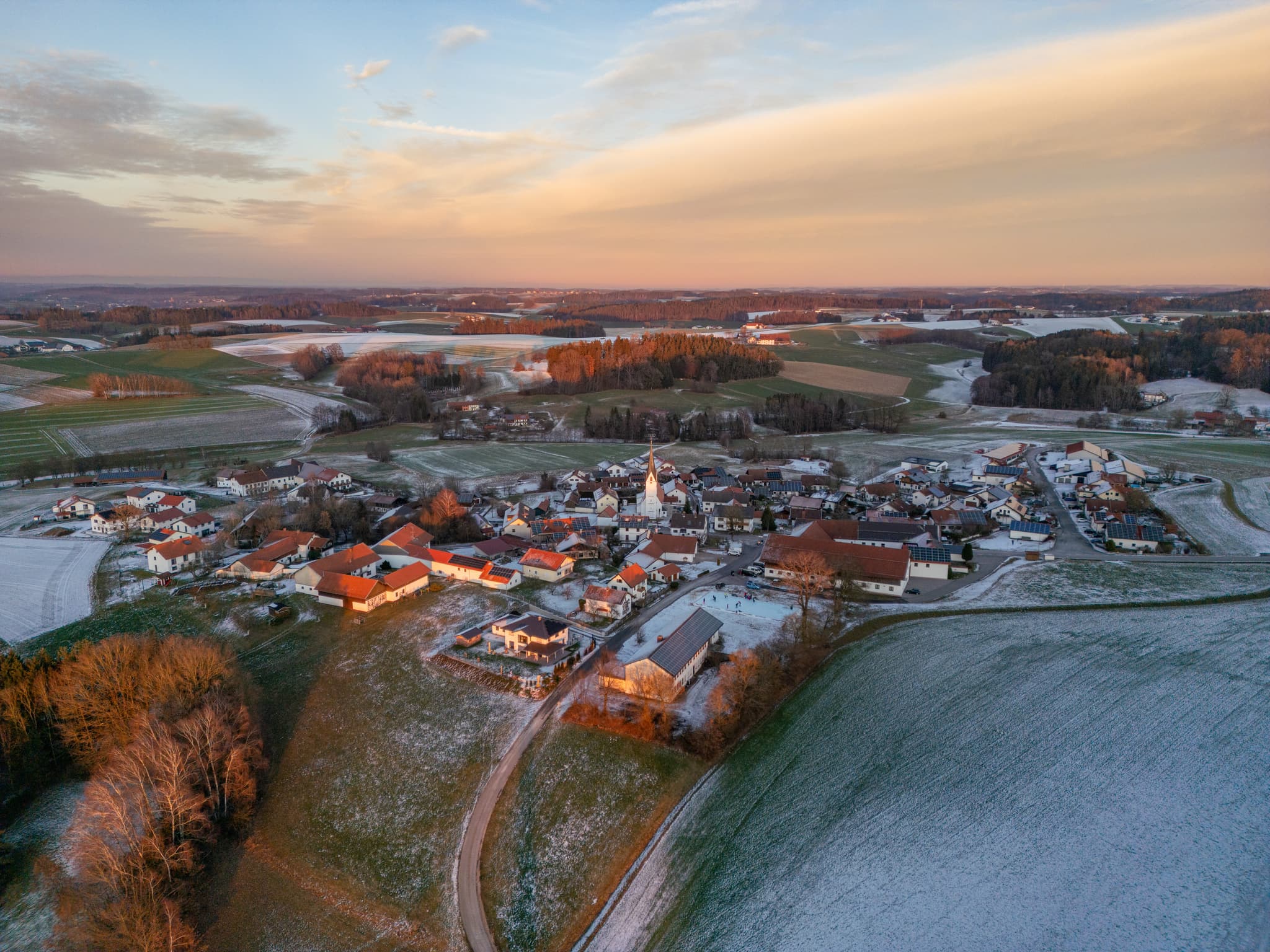 Winterliche Luftaufnahme von Arbing in der Gemeinde Reischach im Landkreis Altötting, Oberbayern, Deutschland. Letzte Wintersonne an der Eisarena.
