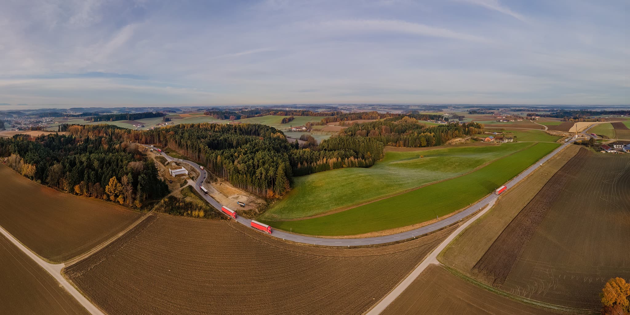 Luftaufnahme der Baustelle Fuchsberg in Reischach, Altötting, Oberbayern. Zeigt Felder, Wald und eine Straßeim Ausbau im Inn-Salzach / Holzland Gebiet.