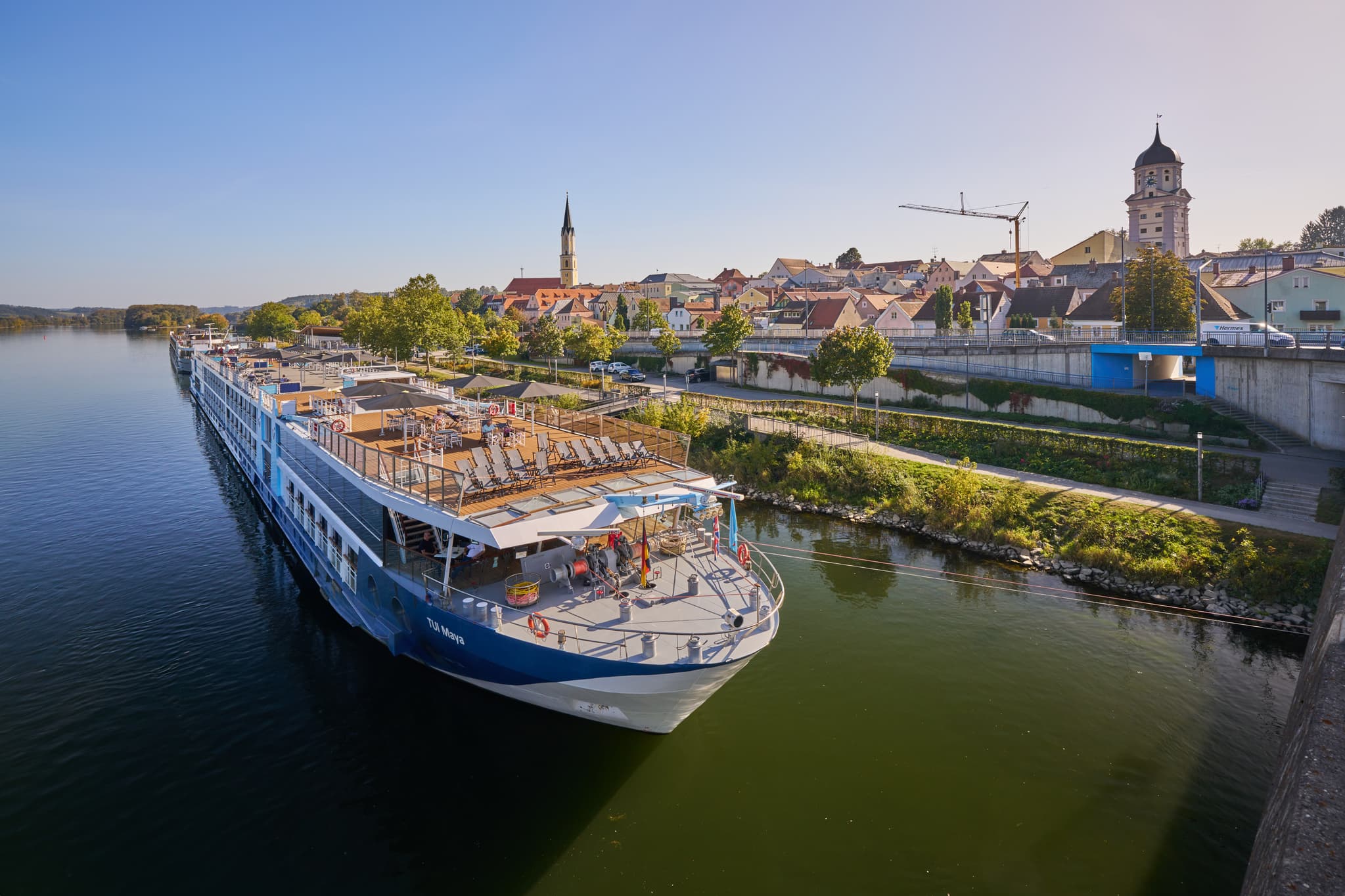 Ein Flusskreuzfahrtschiff am Donau Hafen in Vilshofen, Landkreis Passau, Niederbayern. Stadtkulisse am Donau-Ufer in der Region Donau-Wald, Deutschland.