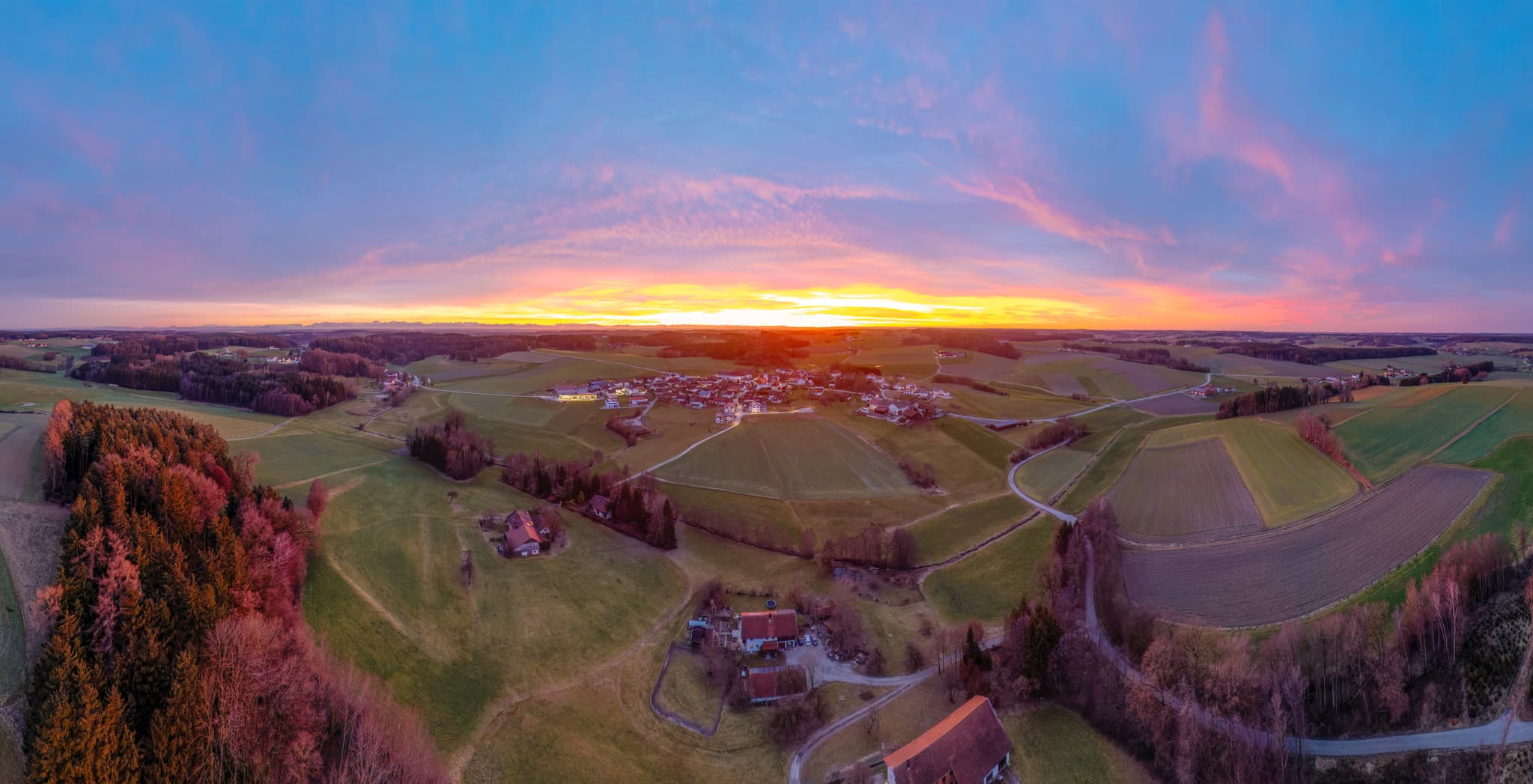 Luftbildpanorama von Arbing, Reischach, Landkreis Altötting, Oberbayern, Inn-Salzach, Deutschland. Ländliche Landschaft mit Feldern, Dorf bei Sonnenuntergang.