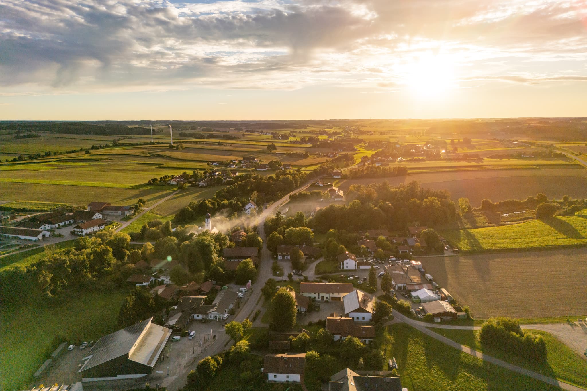 Ortsansicht Dirnaich, Gangkofen, Rottal-Inn, Niederbayern. Ein Windpark prägt die Landschaft im Holzland. Weite Felder unter Sonnenuntergang in Deutschland.