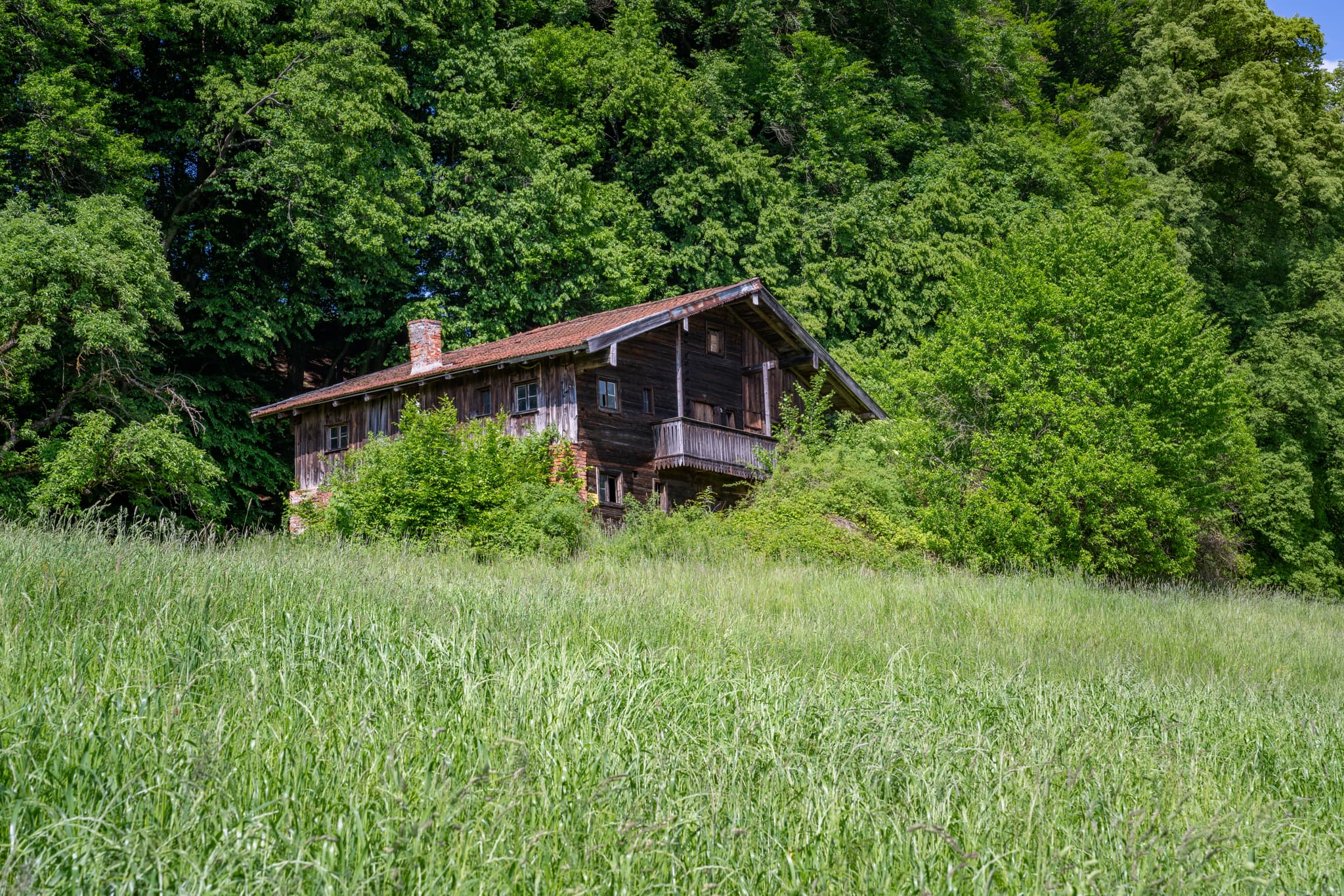 Kager Indobl, Reischach, Altötting, Oberbayern, Inn-Salzach, Deutschland zeigt ein altes Haus umgeben von Natur auf einer Wiese, nahe dem Waldrand.