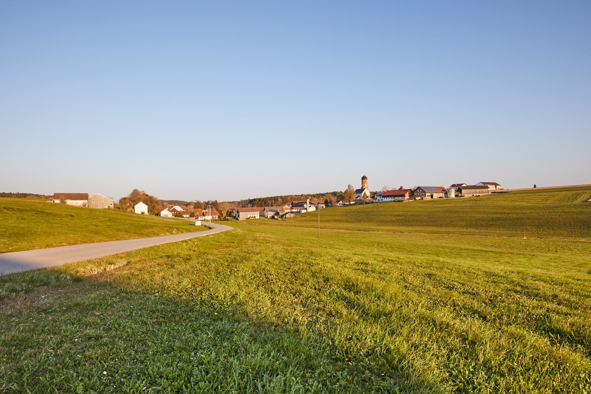 Landschaft bei Martinskirchen, Wurmannsquick, Landkreis Rottal-Inn, Niederbayern. Weite grüne Felder und das Dorf mit Kirchturm im Holzland, Deutschland.