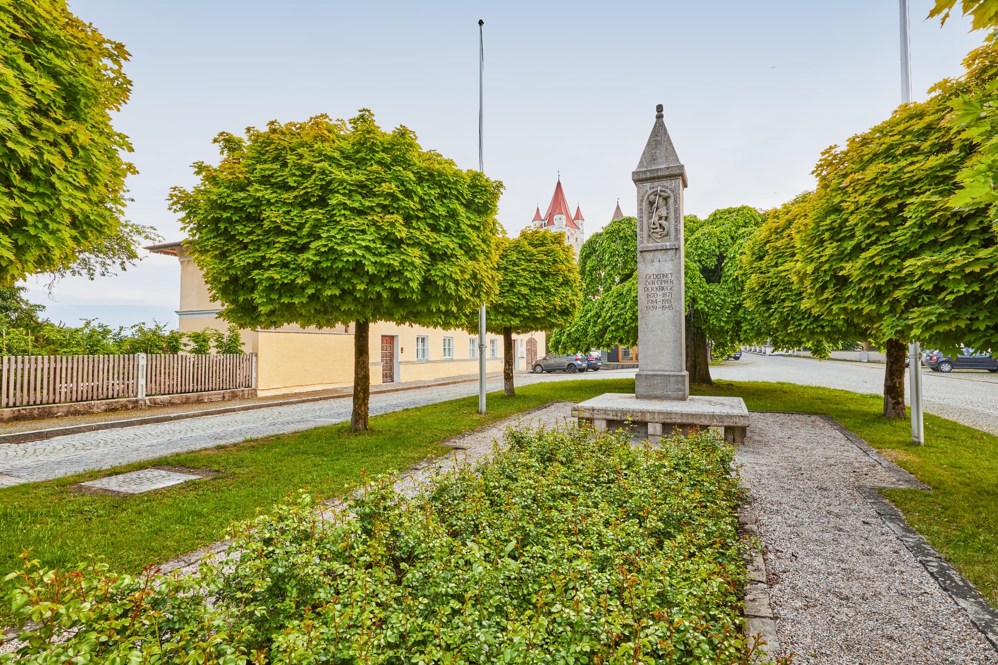 Kriegerdenkmal in Haag, Landkreis Mühldorf am Inn, Oberbayern, Deutschland. Typische Szenerie der Region Inn-Salzach mit Grün, Bäumen und Gebäuden.