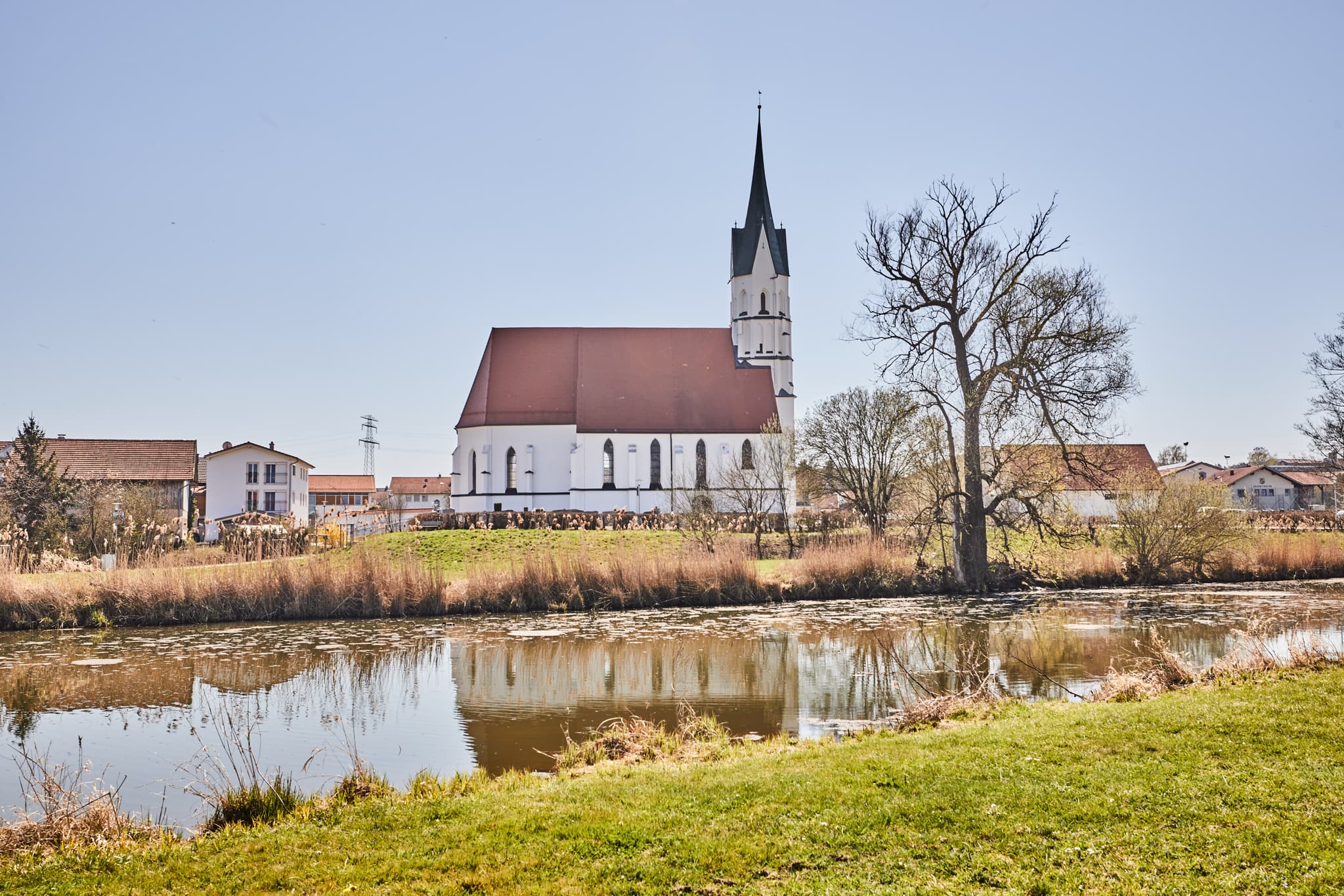 Stattliche Kirche mit hohem Turm, Spiegelung im Gewässer, Unterdietfurt, Landkreis Rottal-Inn, Niederbayern. Ländliche Landschaft im Holzland, Deutschland.