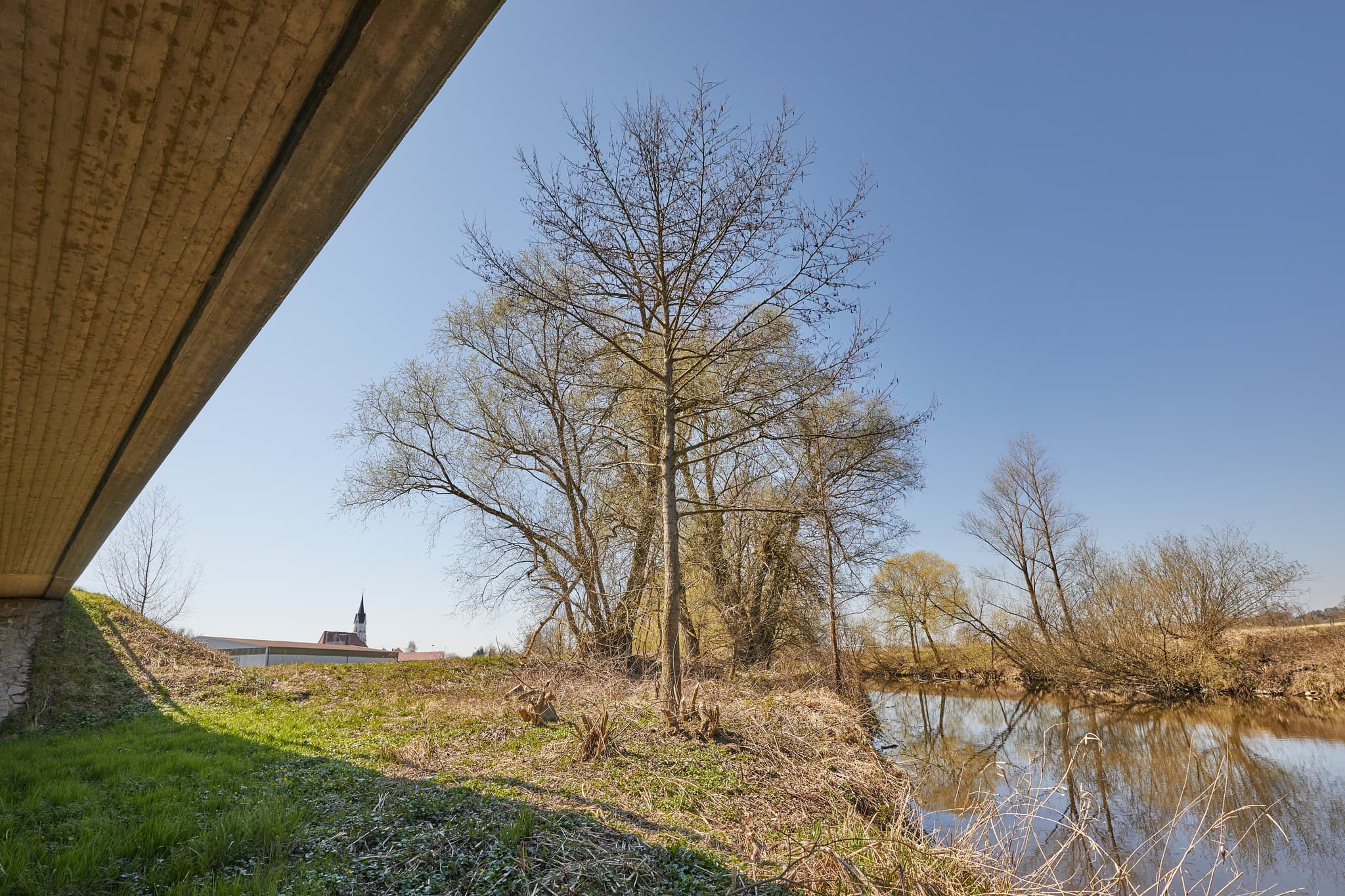 Rott Brücke in Unterdietfurt, Rottal-Inn, Niederbayern. Betonbrücke überquert die Rott. Landschaft im Holzland, Deutschland, mit Bäumen und Ufer. Frühlingstag.