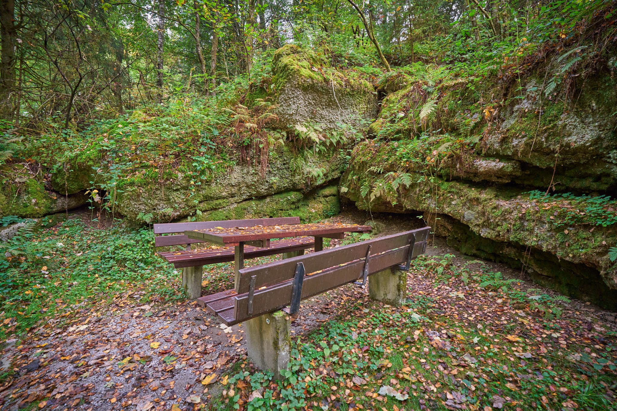 Picknicktisch und Bänke vor felsiger Felsformation im Wald. Bad Griesbach, Landkreis Passau, Niederbayern, Bayerischer Wald, Deutschland.