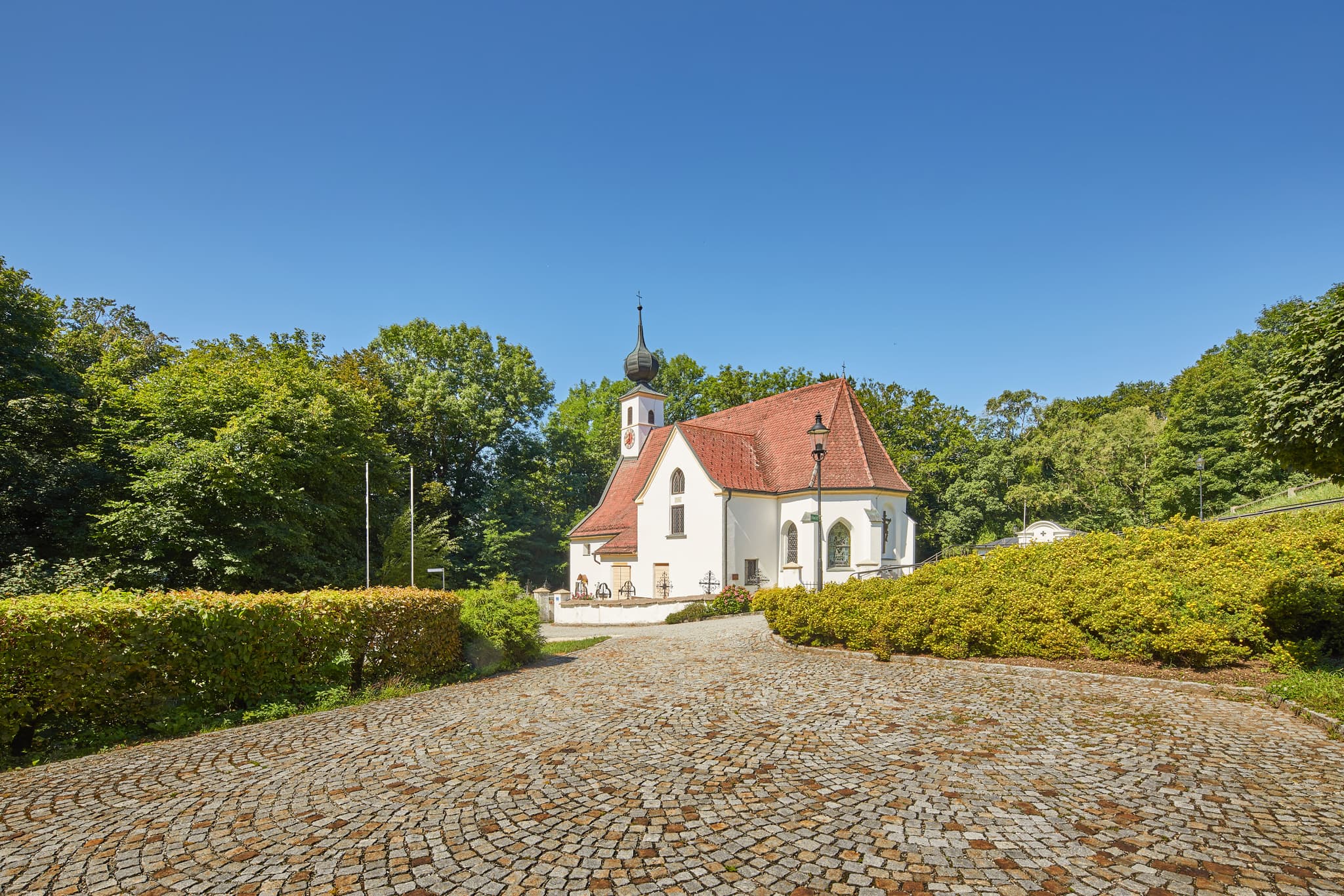 Pfarrkirche Radegundis in Hadermarkt, St. Radegund, Braunau am Inn, Oberösterreich, Innviertel, Österreich. Kirchengebäude in grüner Landschaft.