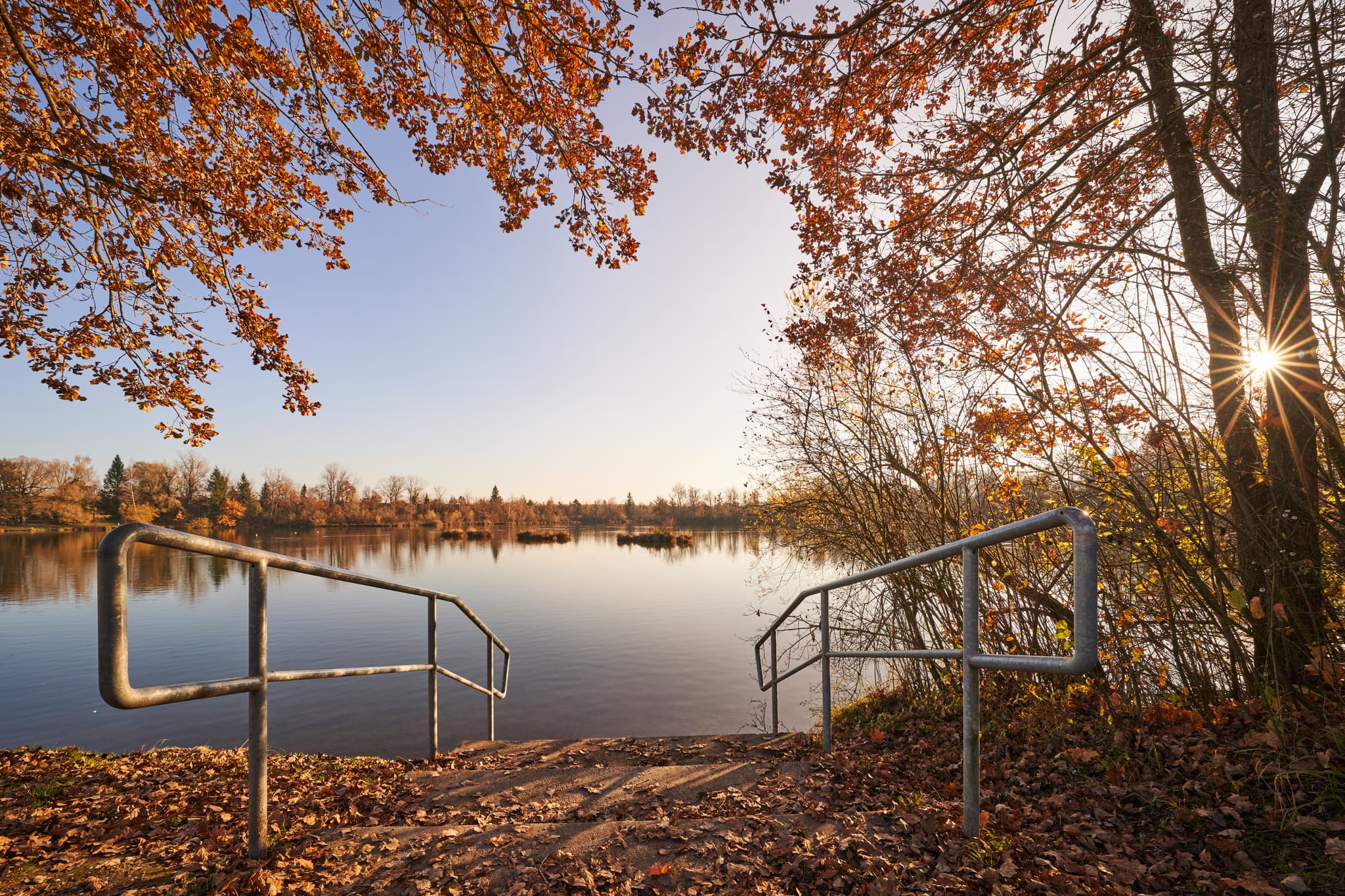 Herbstliche Szene am Waldsee Lago, Kirchdorf am Inn, Rottal-Inn, Niederbayern. Ruhiger See mit buntem Laub an Bäumen und am Ufer.