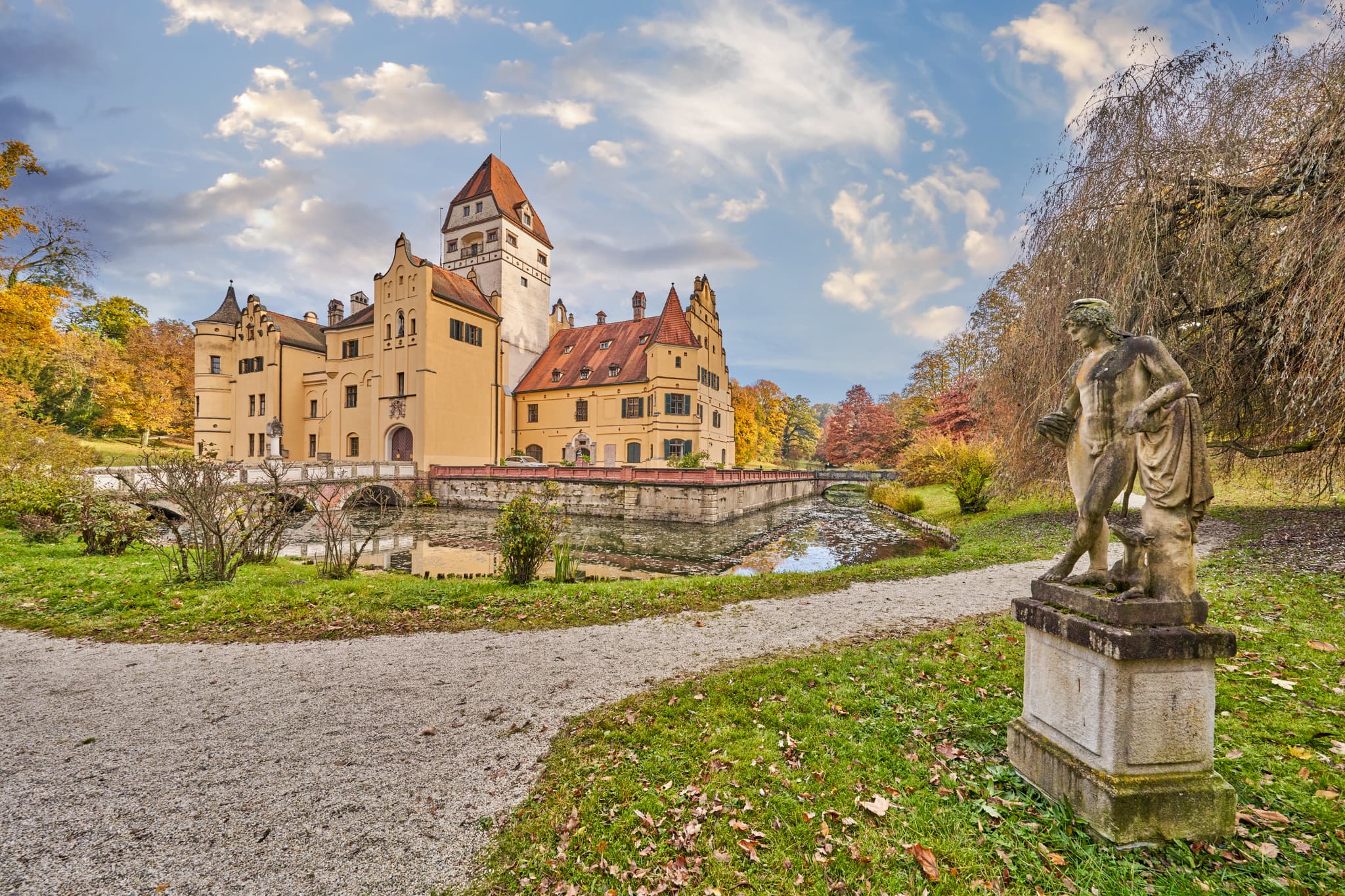 Historisches Schloss Schönau im Schlosspark. Wasserschloss mit Brücke in Rottal-Inn, Niederbayern. Herbstlandschaft im Holzland, Deutschland, Statue und Wege.