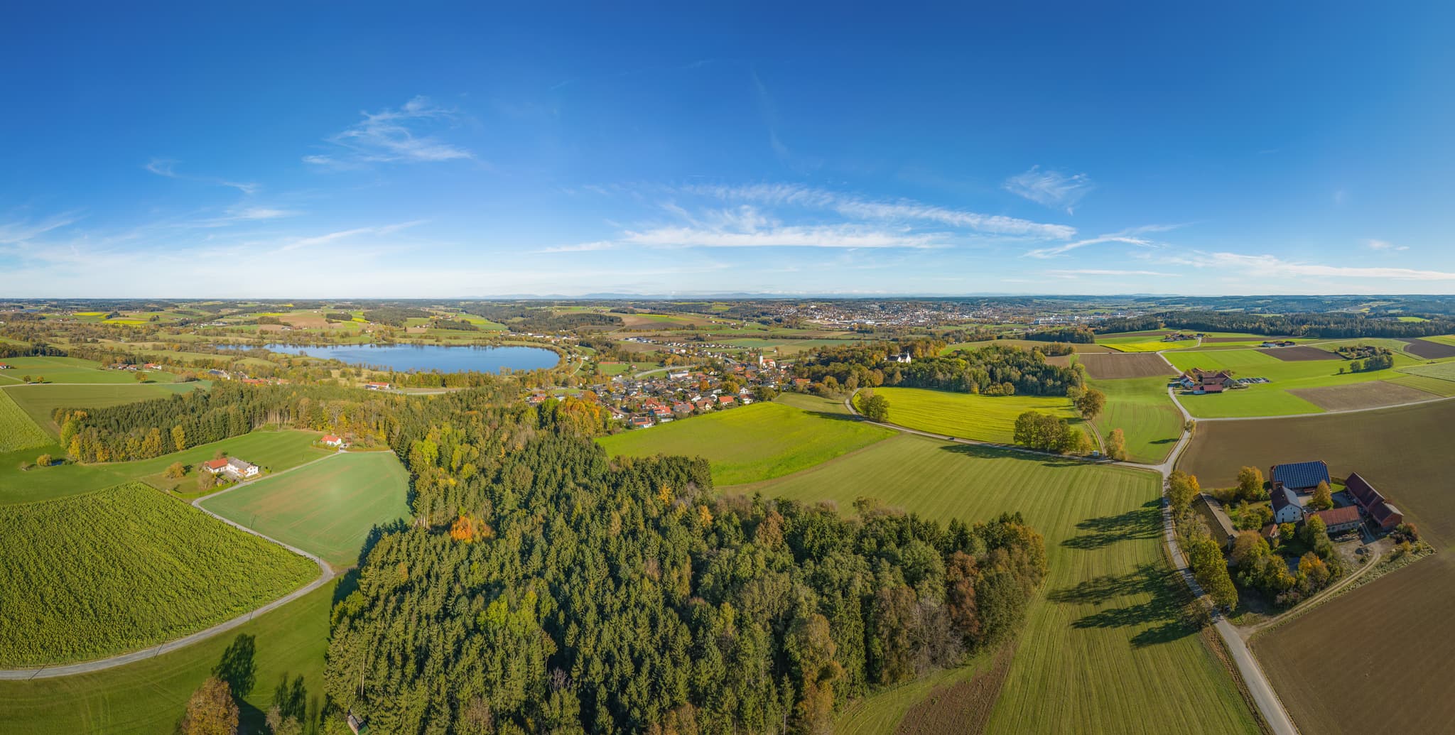 Luftbildaufnahme des Stausees und der umliegenden Landschaft bei Postmünster im Landkreis Rottal-Inn, Niederbayern, zeigt das Holzland mit Feldern und Wald.