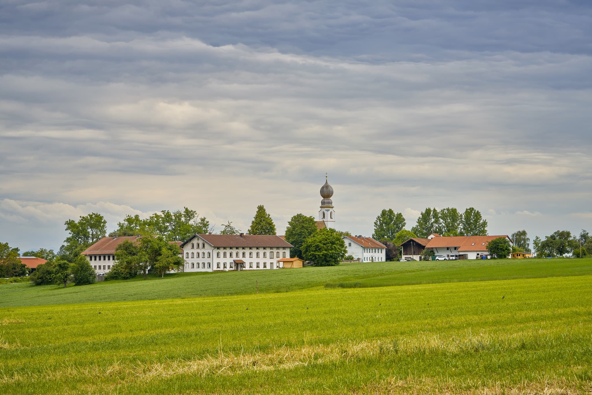 Ortsansicht Kirchweidach bei Neukirchen an der Alz in Oberbayern, Inn-Salzach, Deutschland. Idyllisches Landschaftsbild mit Kirche und Häusern.