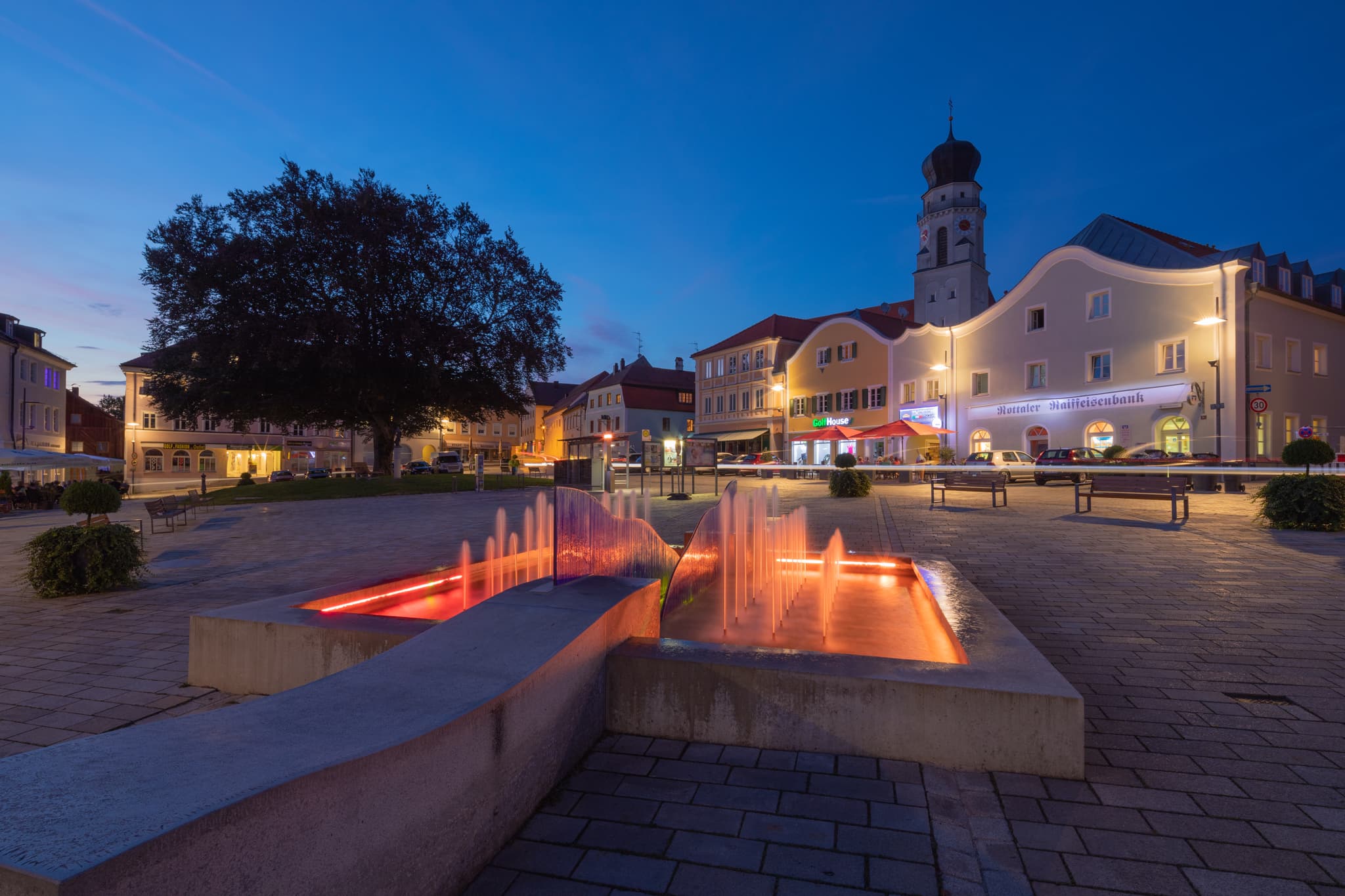 Der Stadtplatz Brunnen in Bad Griesbach im Rottal, Landkreis Passau, Niederbayern, Deutschland zur blauen Stunde. Eine idyllische Abendstimmung.