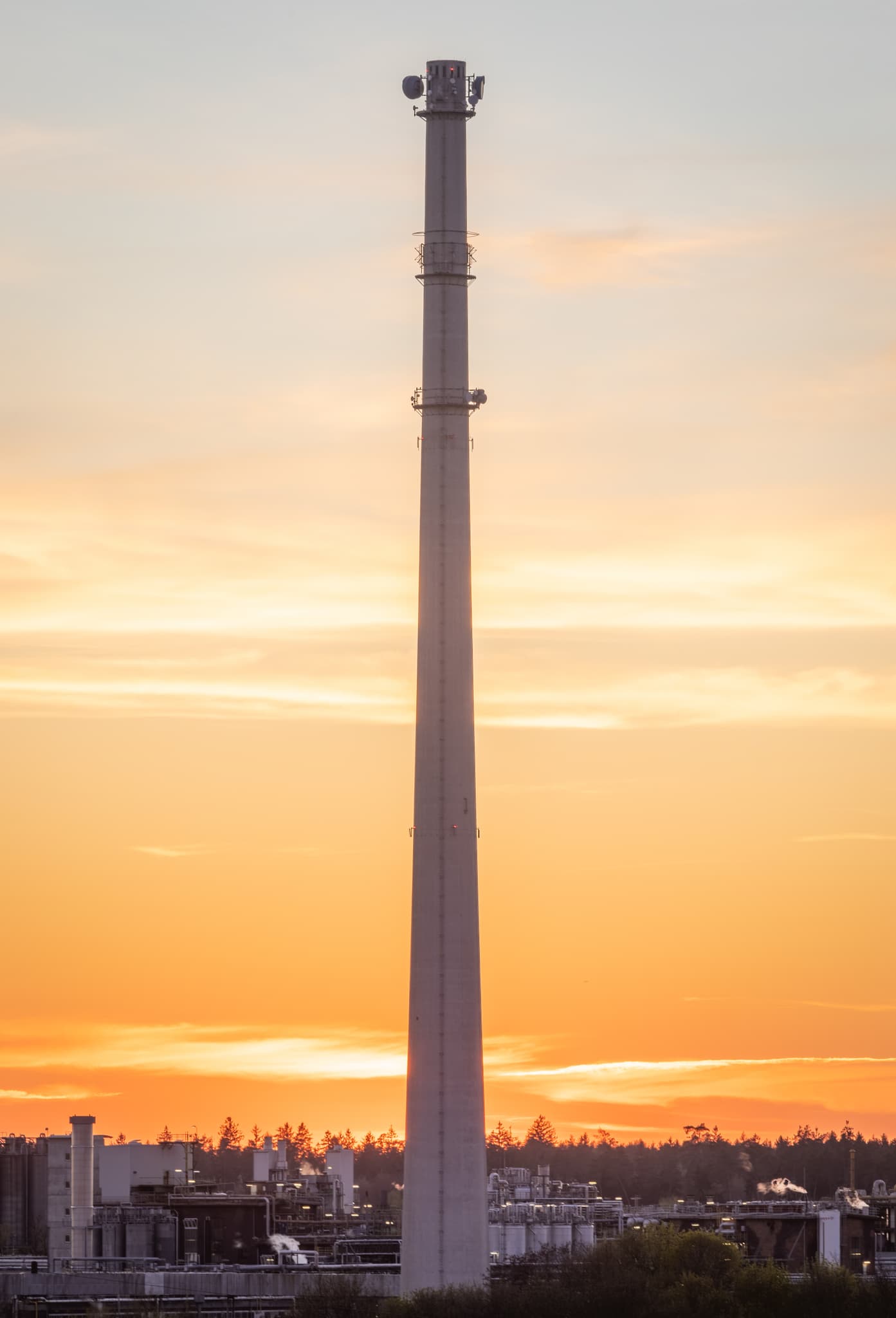 Der markante Turm des Werks Gendorf bei Burgkirchen, Landkreis Altötting, Oberbayern. Eine Industrieanlage in der Inn-Salzach Region bei Sonnenuntergang.