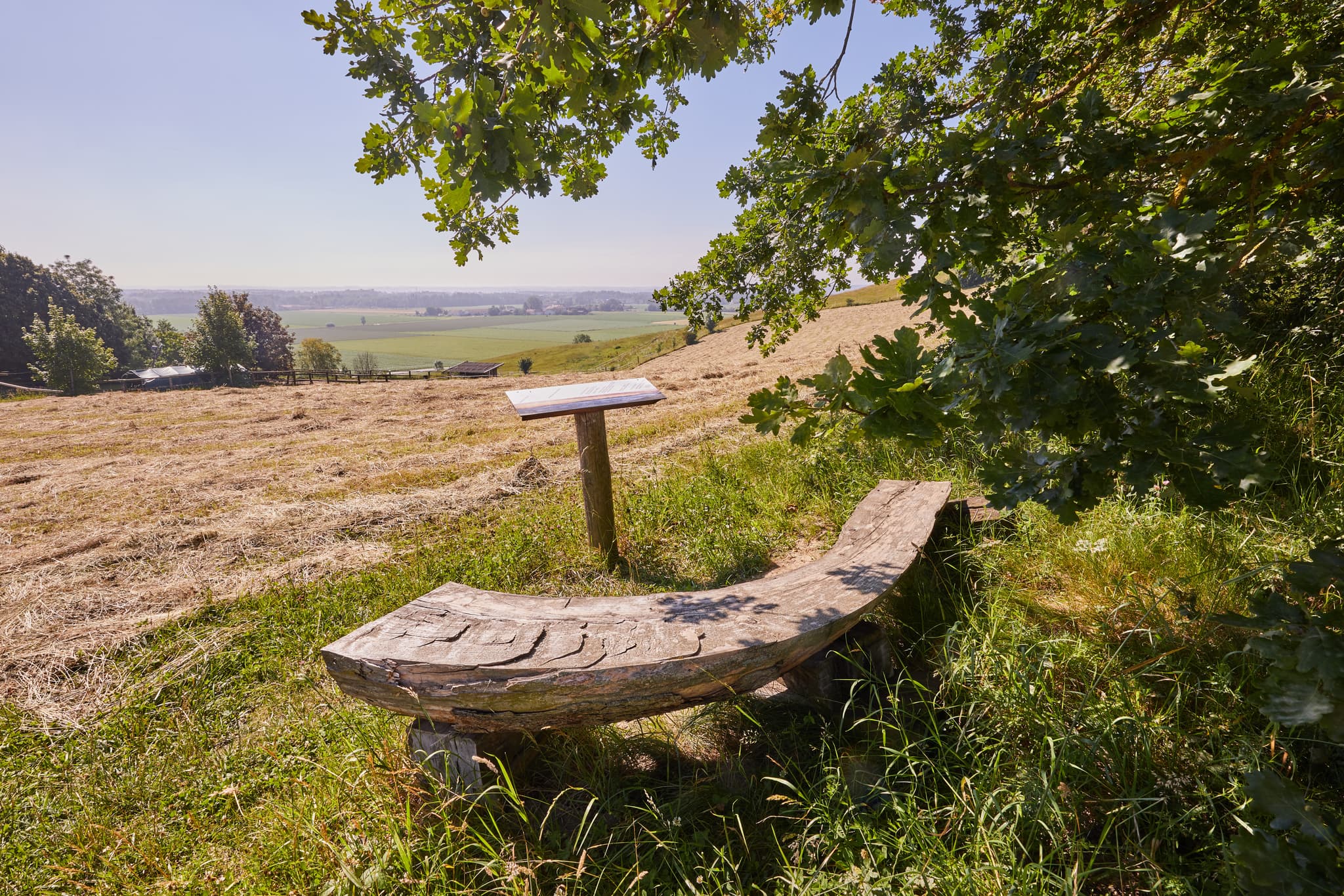 Holzbank auf dem Glatzberg in Heldenstein, Aussicht über Felder und Hügel des Landkreises Mühldorf am Inn, Oberbayern, Region Inn-Salzach, Deutschland.