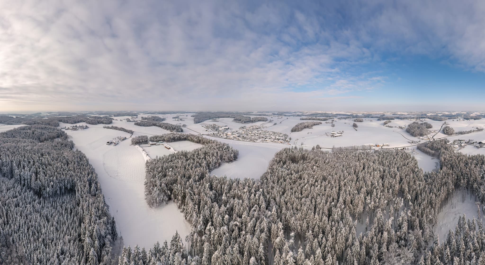 Panoramisches Luftbild einer malerischen Winterlandschaft rund um den Sportplatz in Erlbach, Landkreis Altötting, Oberbayern, Region Inn-Salzach, Deutschland.