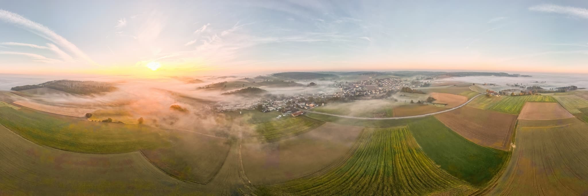 Blick auf Kößlarn, Markt im Landkreis Passau, Niederbayern, Deutschland. Landschaft im Donau-Wald mit Feldern und Hügeln, eingehüllt in Nebel zum Sonnenaufgang.