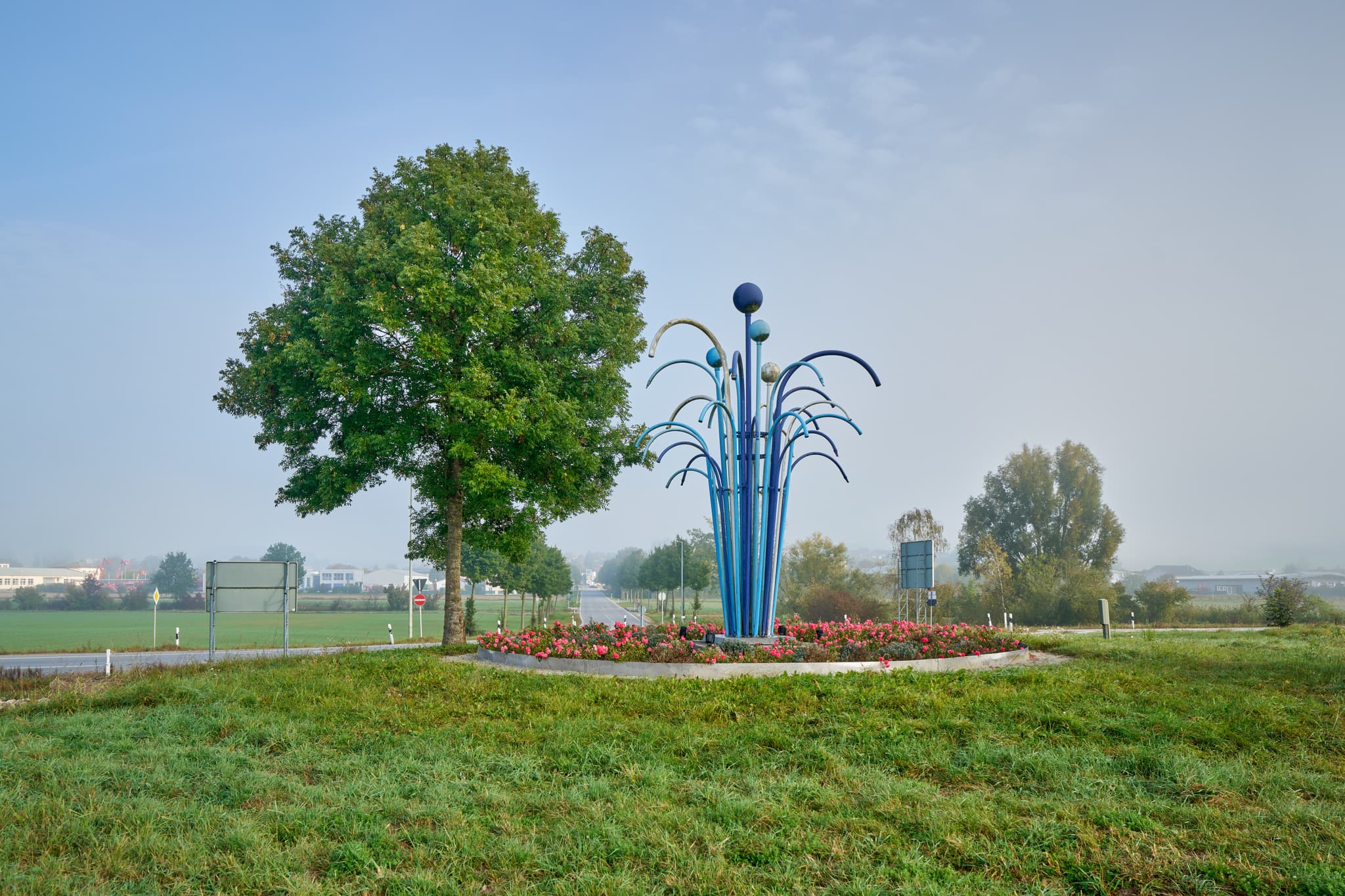 Herbststimmung in Bad Birnbach, Rottal-Inn, Niederbayern. Kreisverkehr mit moderner Skulptur und Baum, eingebettet in die ländliche Landschaft des Bäderdriecks.