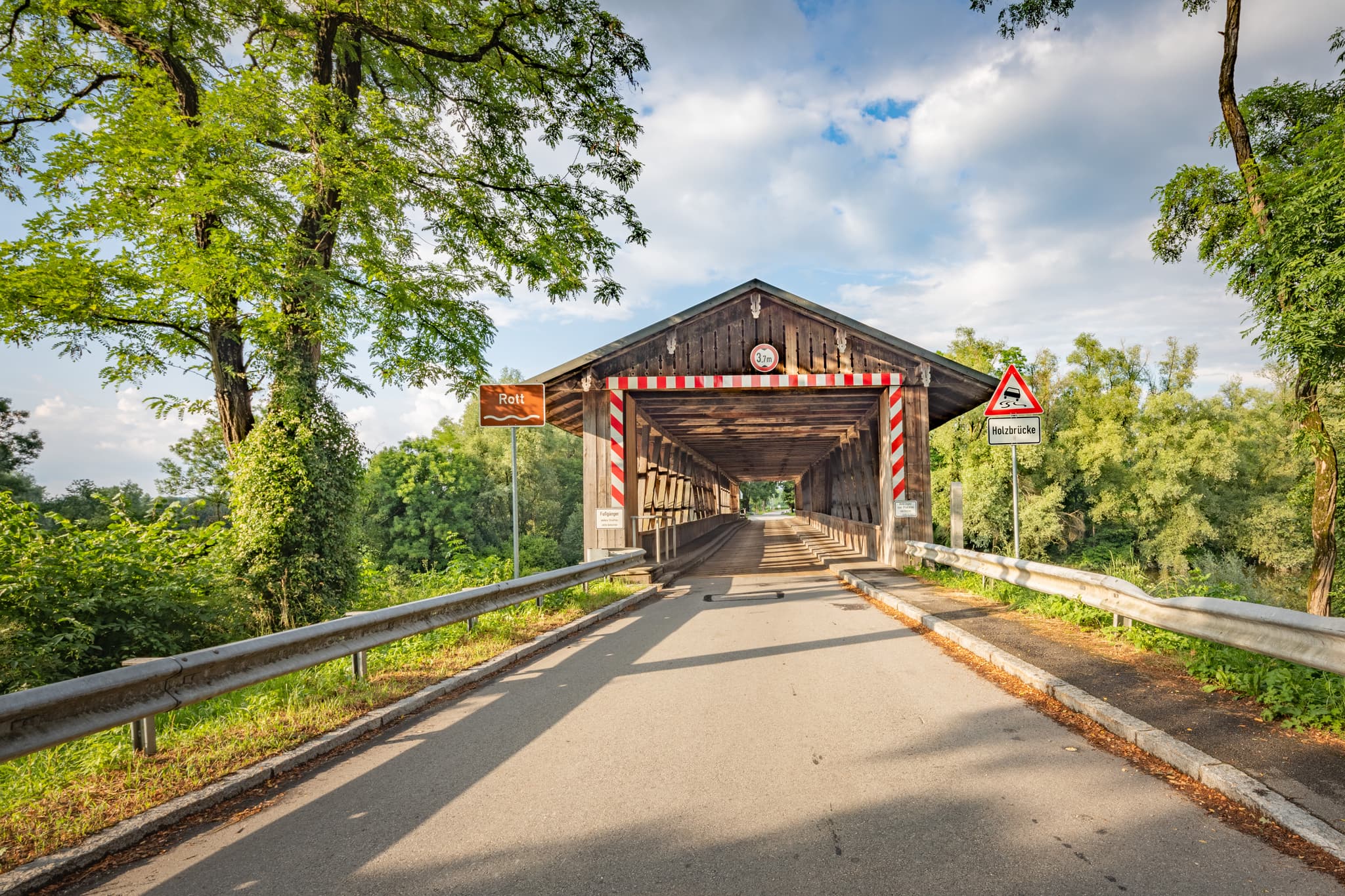 Die historische Holzbrücke Rottbrücke in Neuhaus am Inn, Landkreis Passau, Niederbayern, Deutschland. Ein malerisches Motiv inmitten grüner Natur.
