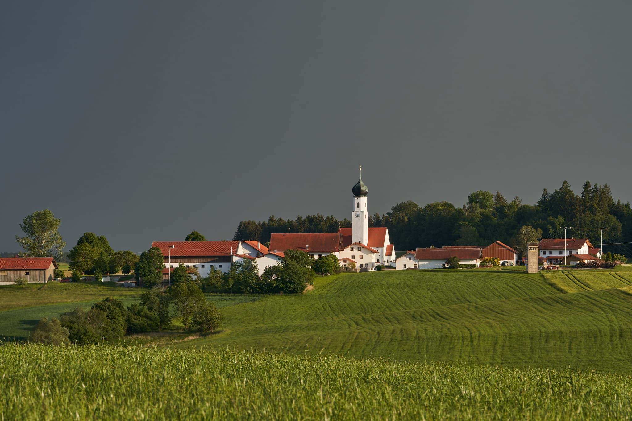 Öging Richtung Endlkirchen, Gemeinde Erlbach im Landkreis Altötting, Oberbayern, Deutschland, Region Inn-Salzach. Landschaft mit Feldern und dunklem Himmel.
