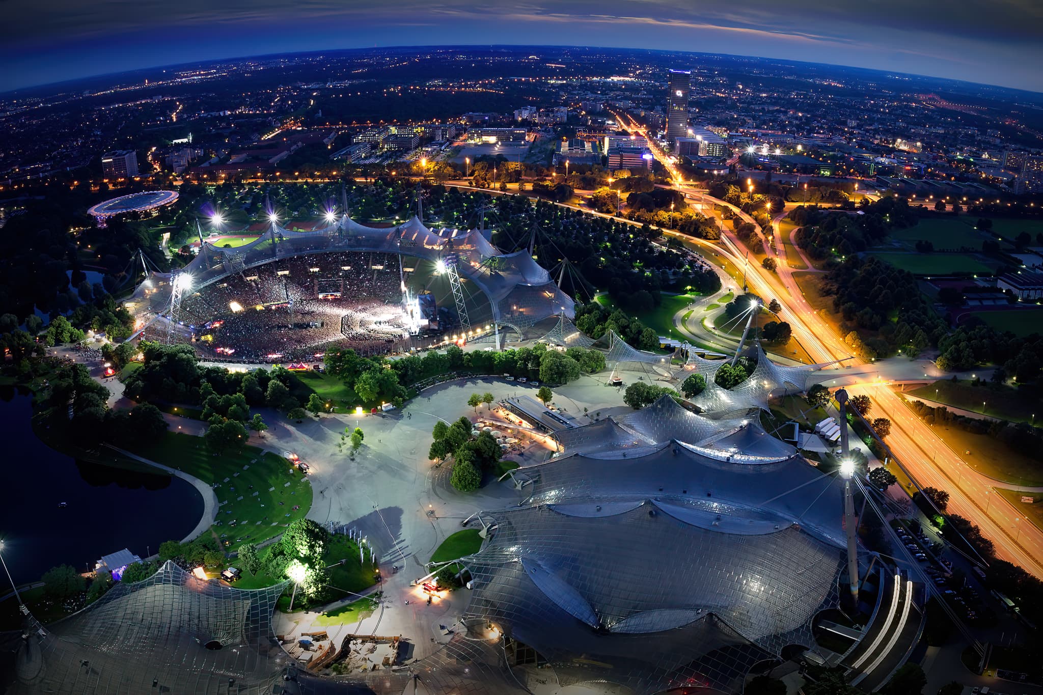 Olympiapark und Olympiastadion in München, Deutschland. Nachtaufnahme mit beleuchteter Architektur, Konzerten, Panorama