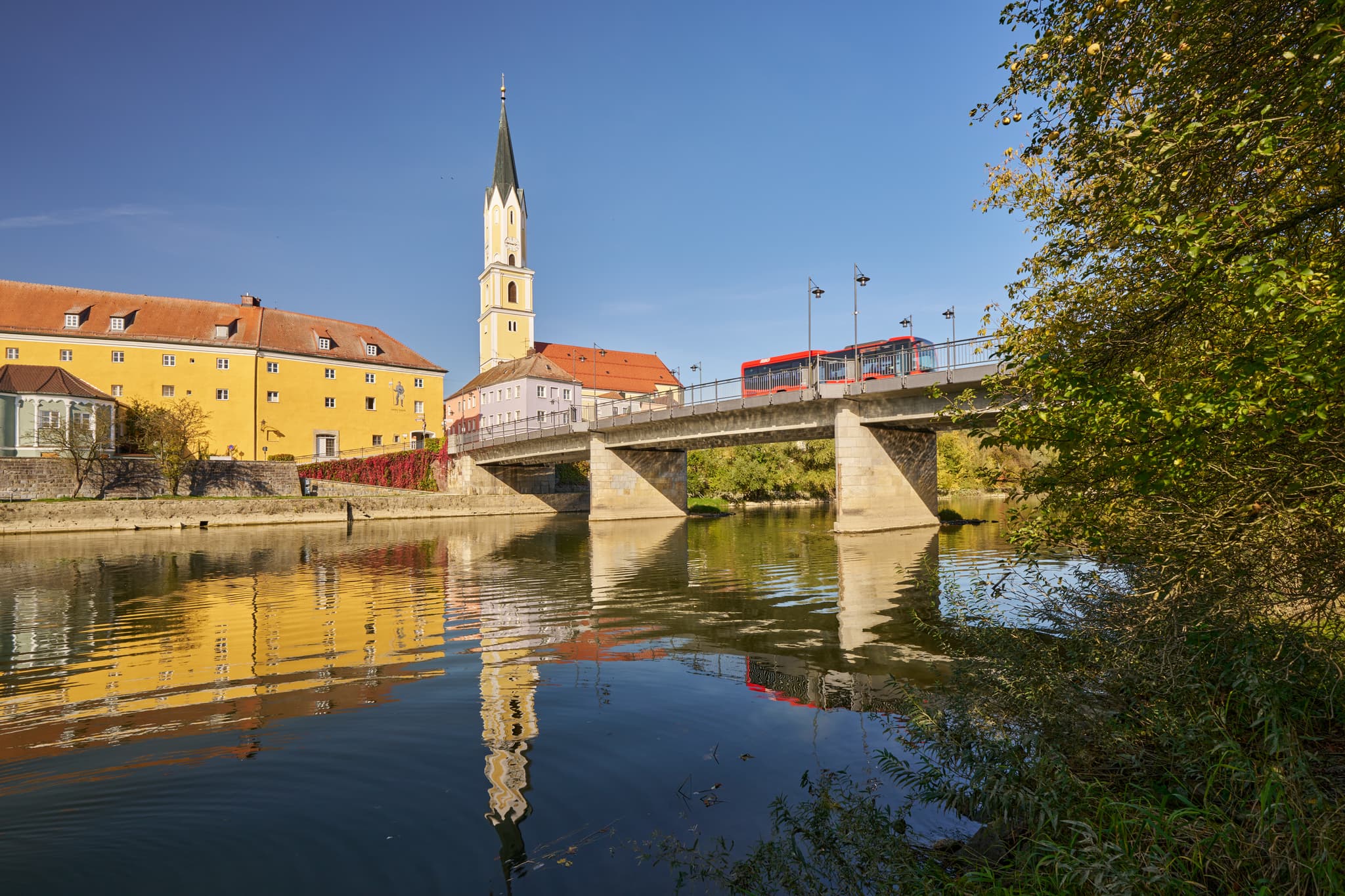 Stadtansicht Vilshofen an der Vils, Landkreis Passau, Niederbayern. Historische Gebäude, Kirchturm und Brücke spiegeln sich im Fluss. Donau-Wald, Deutschland.