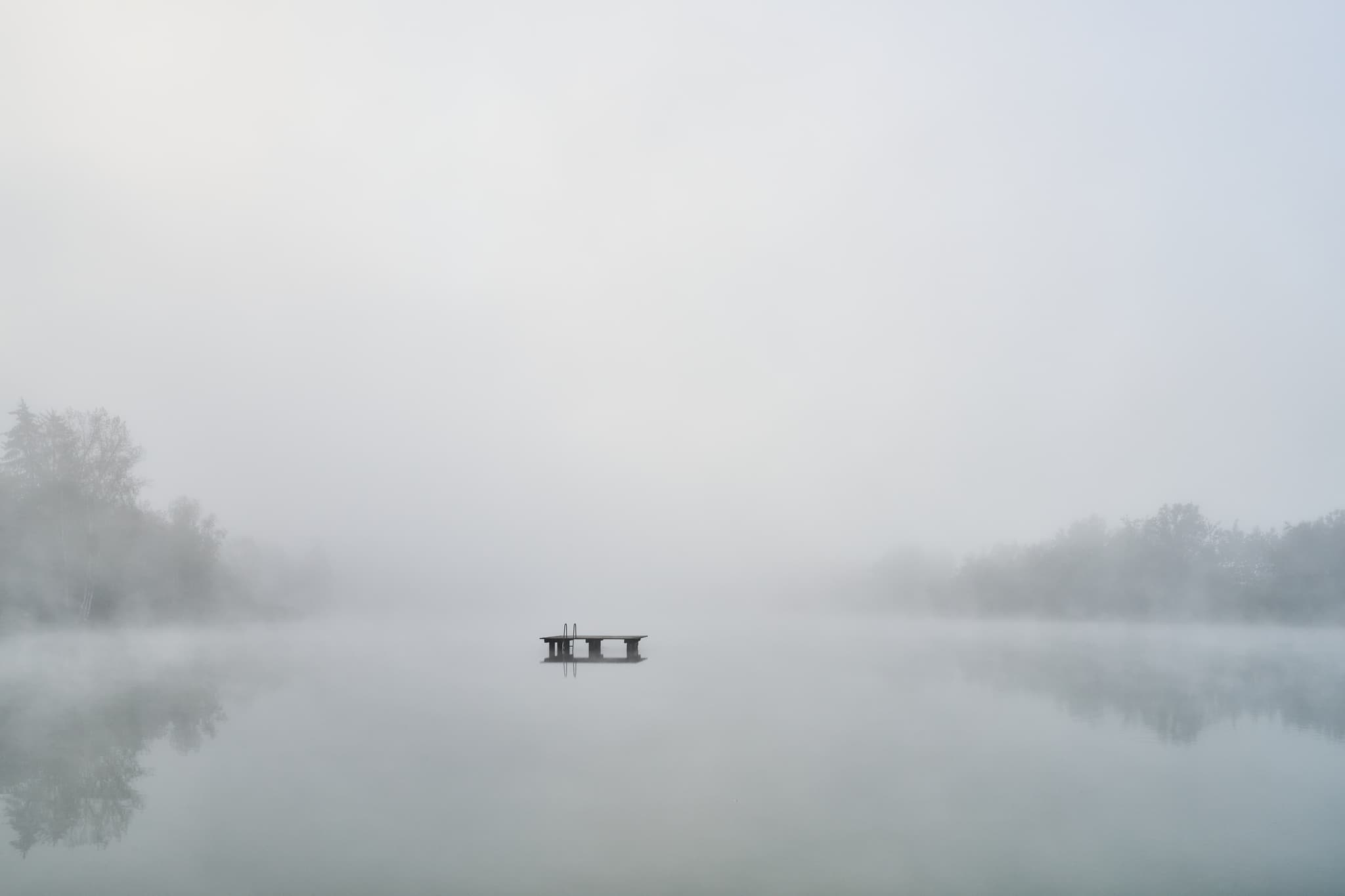 Badesee in Marktl, Altötting, Oberbayern, Deutschland: Morgennebel über dem See. Klare Sicht auf die Landschaft der Region Inn-Salzach.