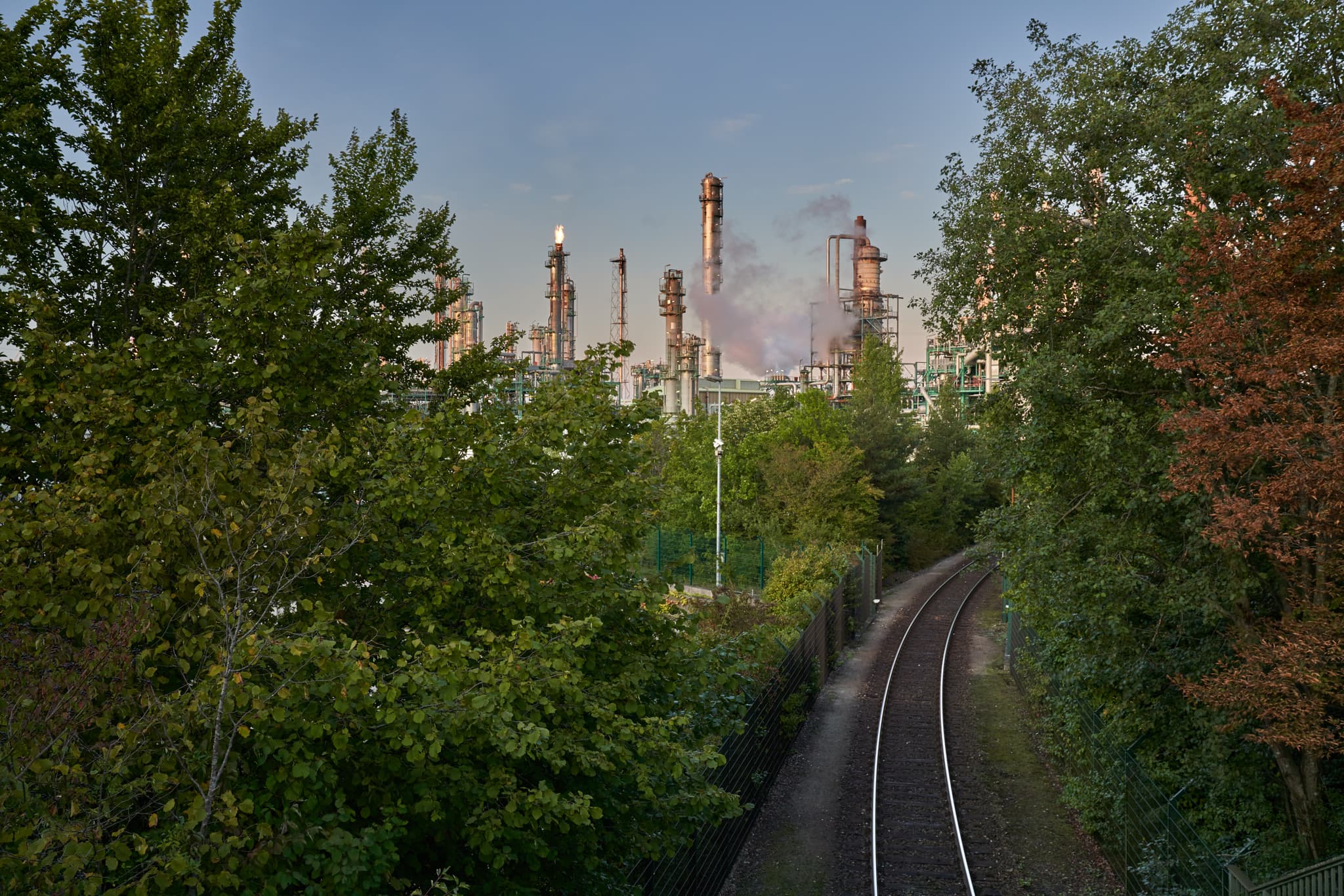 OMV Raffinerie mit Fackelbetrieb und Bahnlinie in Haiming, Burghausen, Landkreis Altötting, Oberbayern, Industrielandschaft.