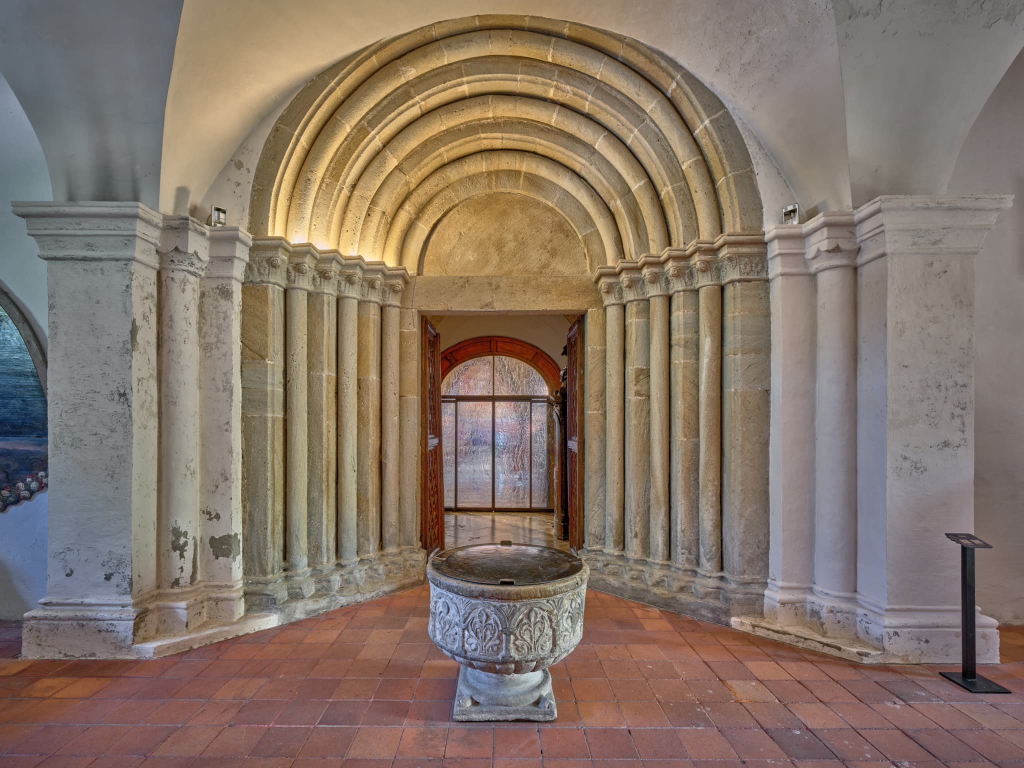 Seiteneingang zur Stiftskirche, romanisches Portal, Altötting, Oberbayern. Taufbecken im Vordergrund. Inn-Salzach, Deutschland.