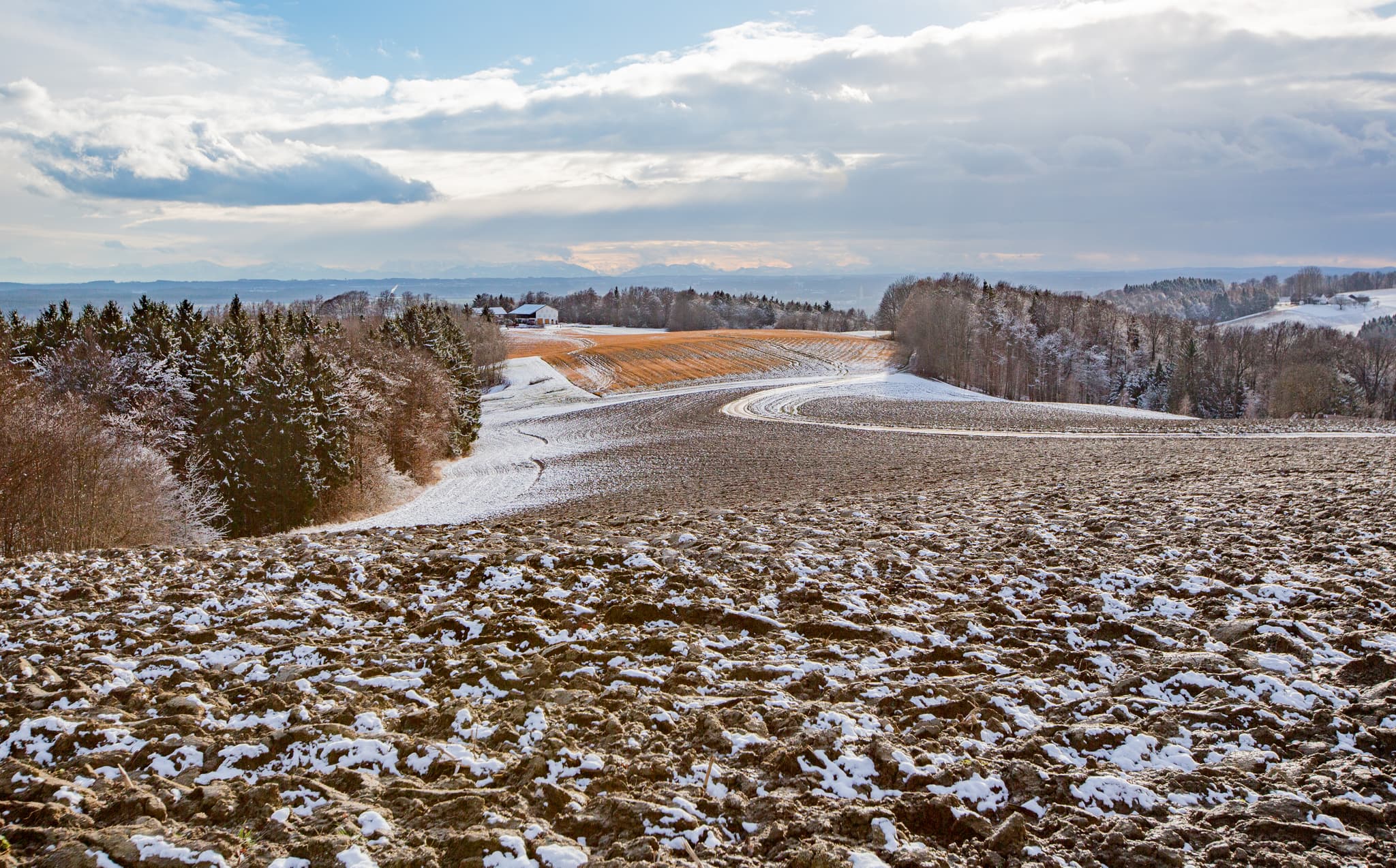 Verschneite Ackerlandschaft mit Feldern und Wäldern von der Friesing Aussicht bei Reischach im Landkreis Altötting, Oberbayern, Inn-Salzach, Deutschland.