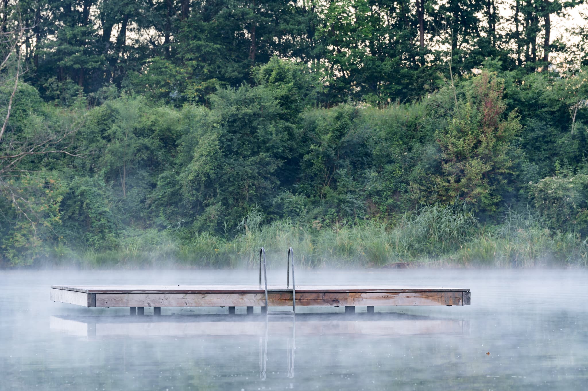 Badesee bei Marktl im Landkreis Altötting, Oberbayern, Deutschland. Das Gewässer liegt im Morgennebel, Teil der malerischen Inn-Salzach Region.