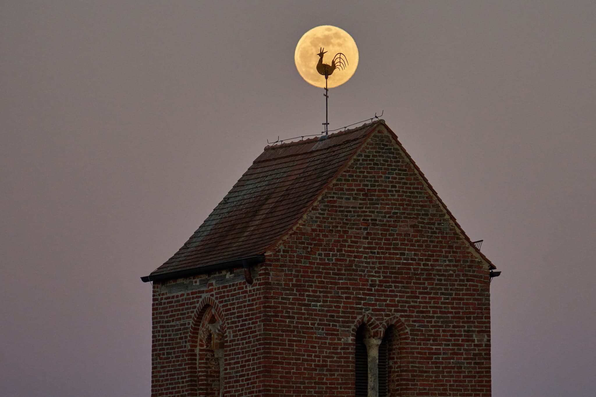Der Kirchturm von Gehersdorf, Zeilarn, Rottal-Inn, Niederbayern, zeigt sich mit dem Mond direkt hinter dem Wetterhahn.