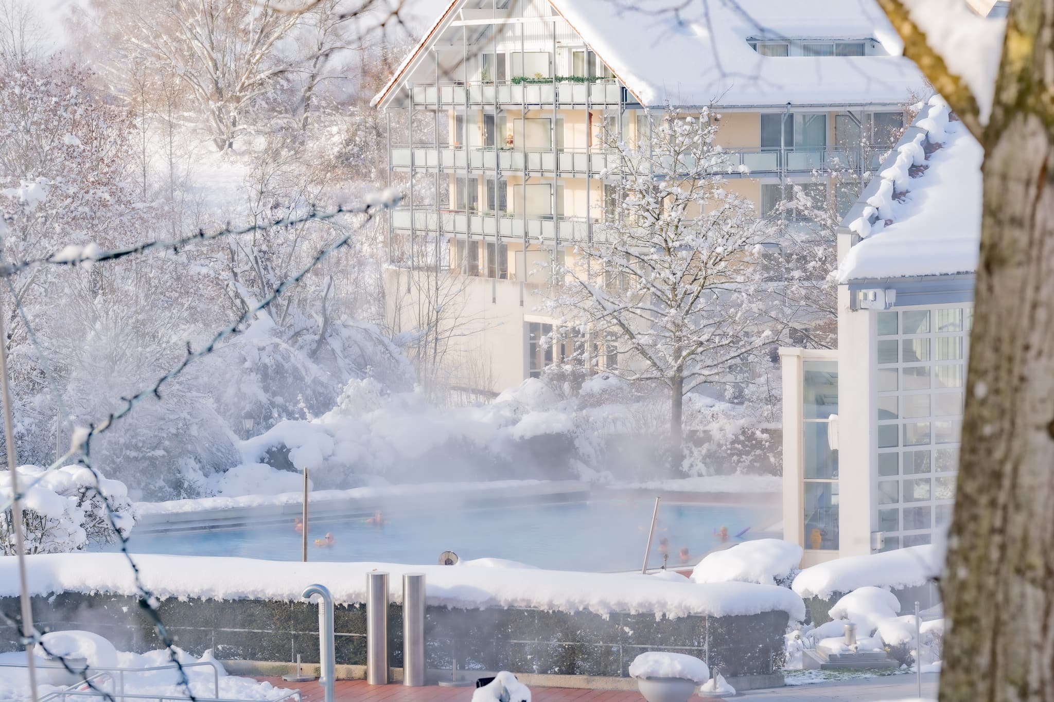 Winterliche Ansicht der Therme in Bad Griesbach, Passau, Niederbayern. Das Bild zeigt das Außenbecken im Schnee, umgebende Gebäuden und verschneiter Landschaft.