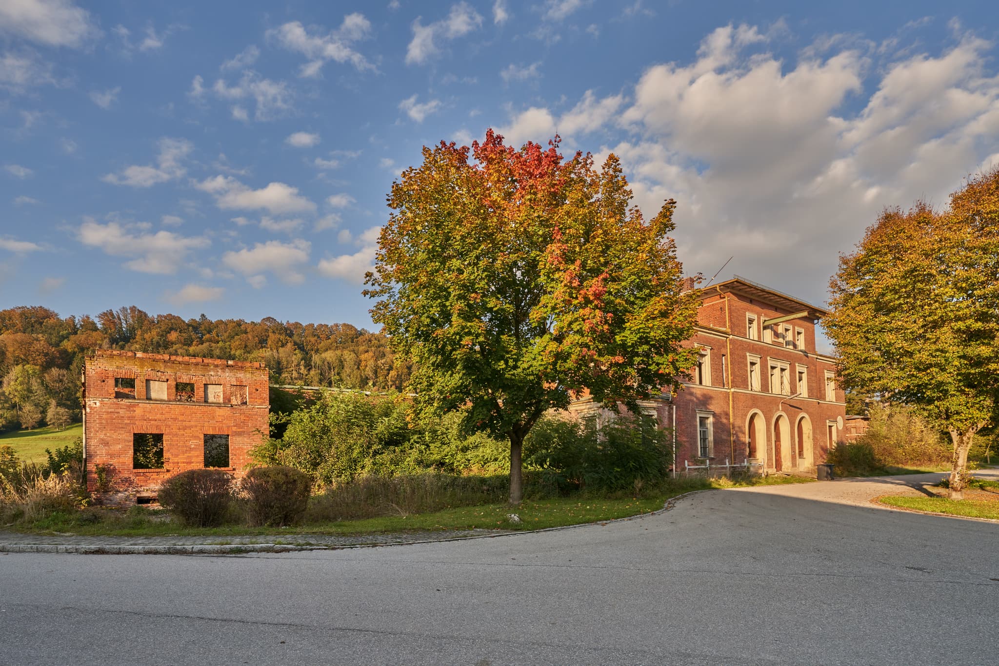 Verlassener Bahnhof Eisenfelden, Winhöring, Altötting, Oberbayern, Deutschland. Herbstlich gefärbte Gebäude und Bäume in der Inn-Salzach Region.
