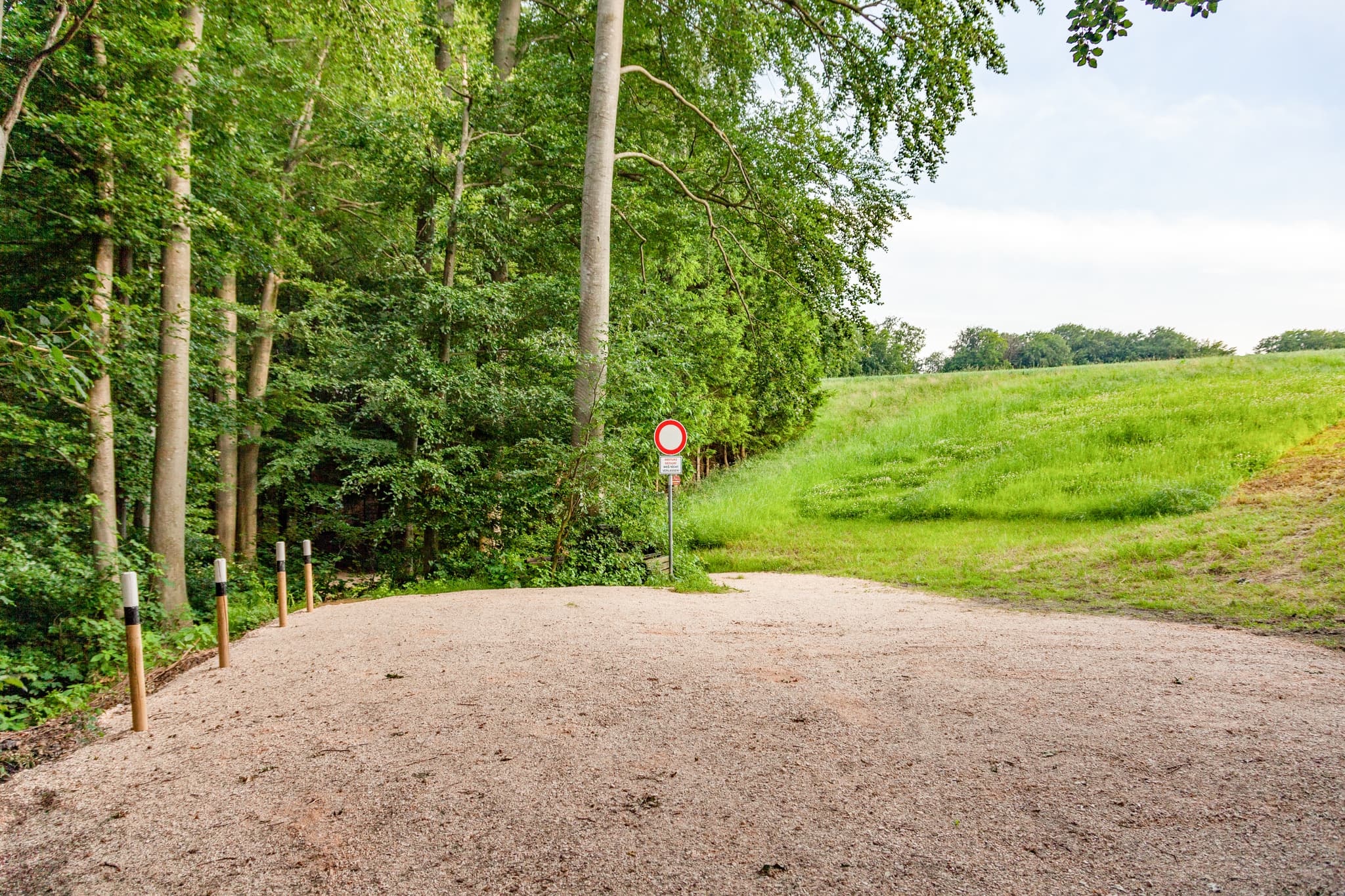Schotterparkplatz am Waldrand mit angrenzender Grünfläche in Oberschroffen, Unterneukirchen, Landkreis Altötting, Oberbayern, Region Inn-Salzach, Deutschland.