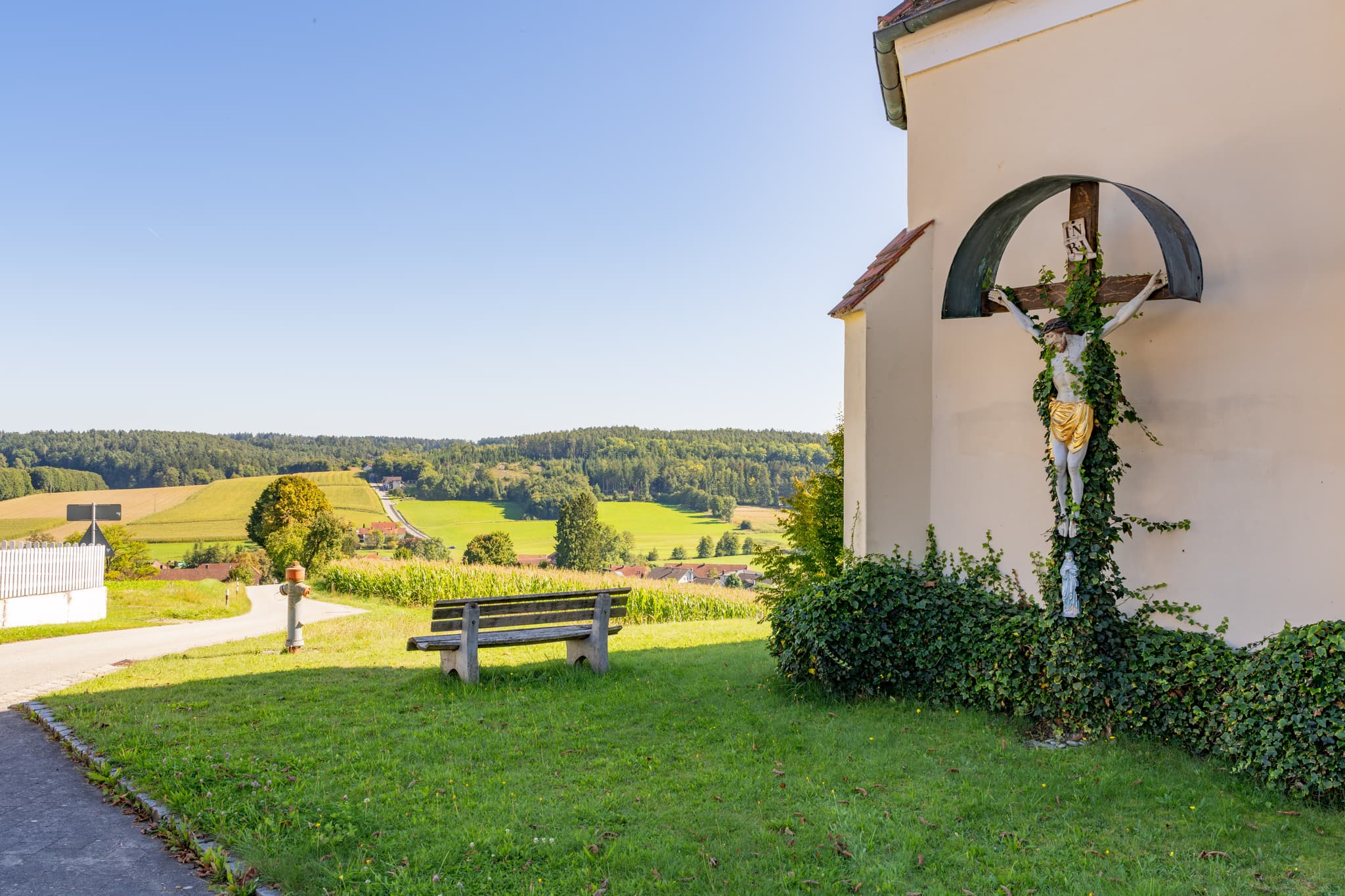 Aussicht ins Sulzbachtal von Wallfahrtskirche Mariä Himmelfahrt, Guteneck, Johanniskirchen, Rottal-Inn, Holzland, Niederbayern. Kruzifix an der Fassade.
