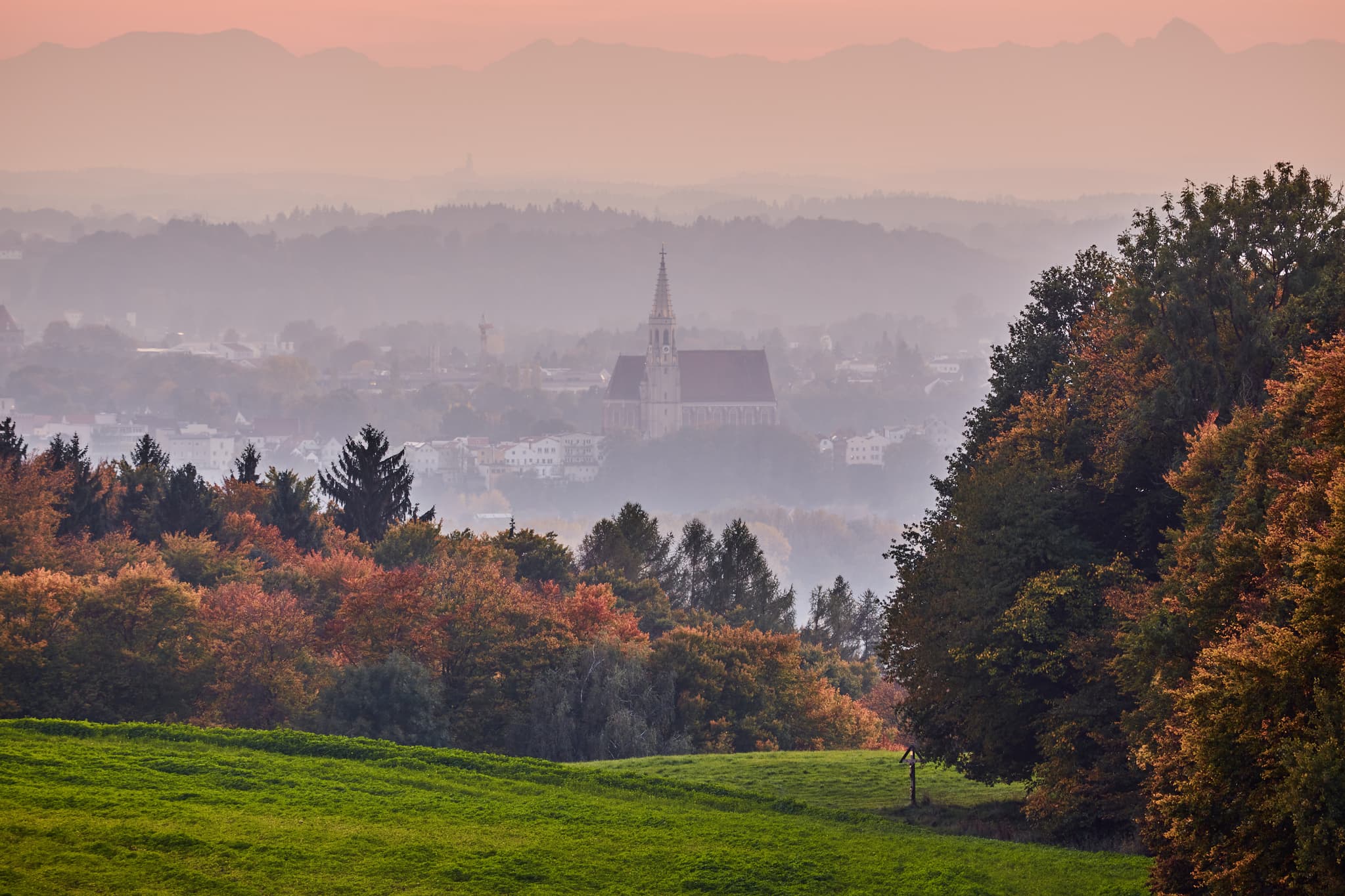 Blick von Friesing Aussicht in Reischach, Altötting, Oberbayern, Inn-Salzach, Deutschland. Zeigt hügelige Landschaft mit Kirche im Dunst, Feldern und Wegen.