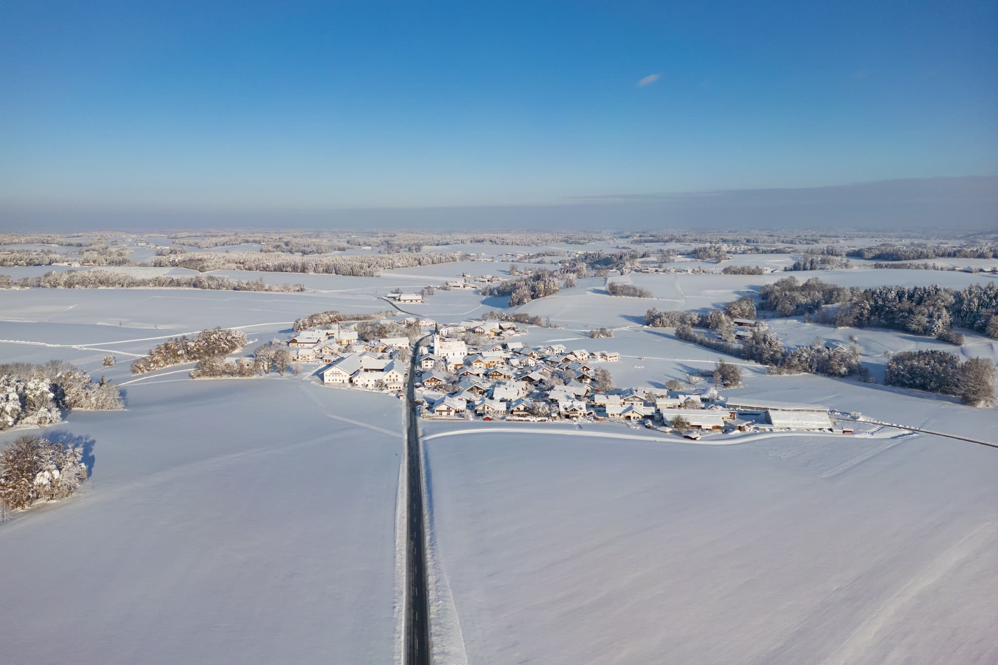 Winterliches Luftbild von Arbing, Reischach, Altötting, Oberbayern. Das Dorf, umgeben von verschneiten Feldern, liegt in Deutschland, Region Inn-Salzach.