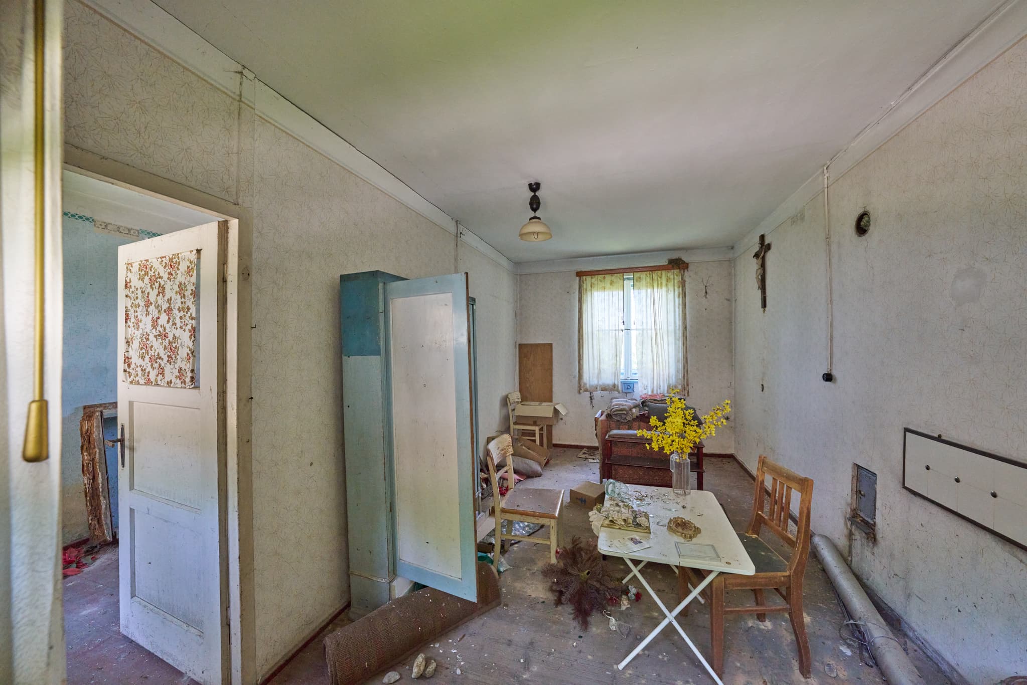Verfallenes Interieur der Alten Wäscherei in Ecksberg, Mühldorf am Inn. Motiv aus Inn-Salzach, Deutschland. Zeigt verlassenen Raum, Möbel, Kruzifix, Blumen.