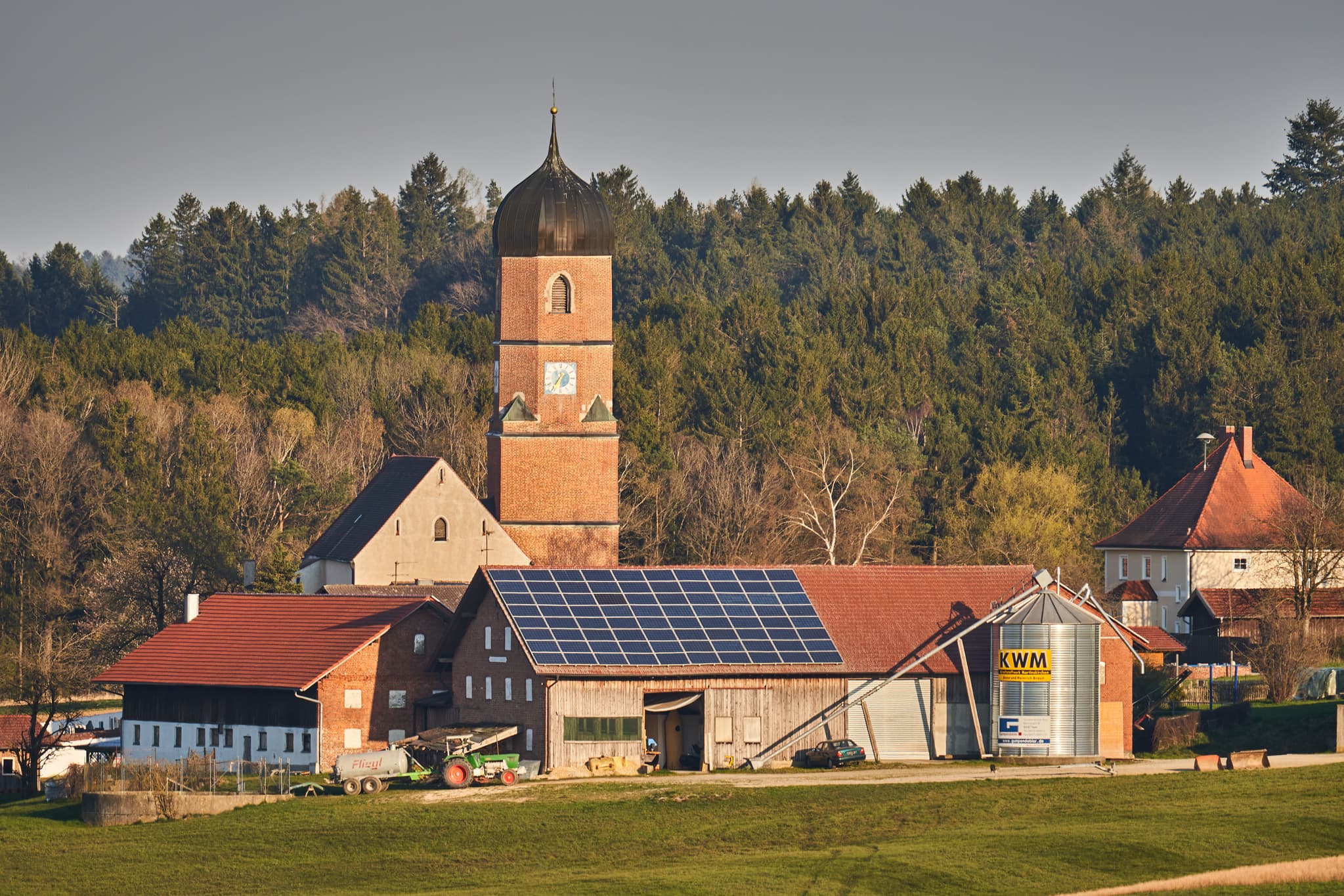Kirche und Bauernhöfe mit Solaranlagen in Martinskirchen, Wurmannsquick, Landkreis Rottal-Inn, Niederbayern. Typische Landschaft des Holzlands, Deutschland.