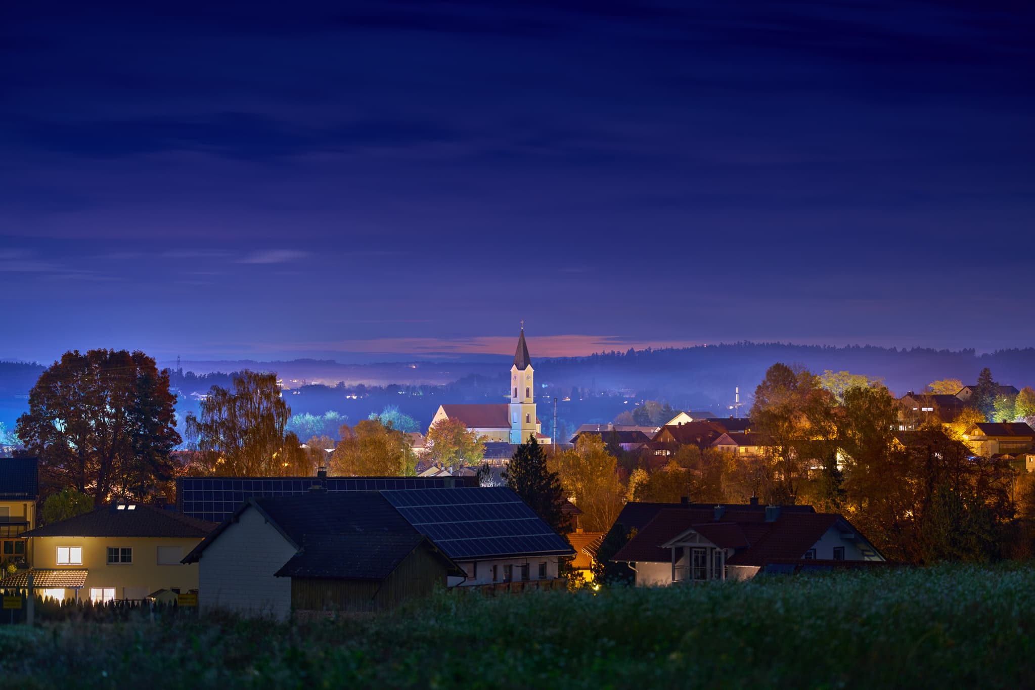 Herbstliche Nachtaufnahme von Mitterskirchen in Niederbayern, Deutschland. Ruhige Abendstimmung mit beleuchteten Häusern und Kirche. Idyllische Landschaft.