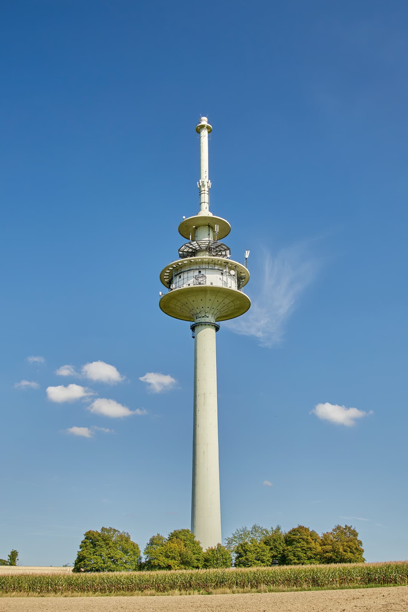 Funkanlage in Schnaitsee, Landkreis Traunstein, Oberbayern, Chiemgau, Deutschland. Hoch aufragender Telekommunikationsturm unter blauem Himmel über weitem Feld.