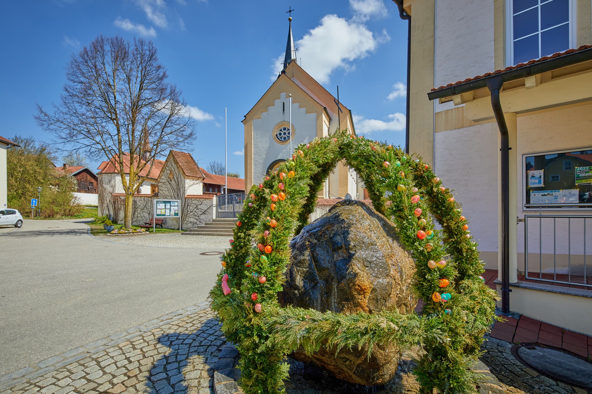 Ein festlich geschmückter Osterbrunnen steht auf dem Dorfplatz in Erlbach, Landkreis Altötting, Oberbayern, Inn-Salzach, Deutschland. Gelebtes Brauchtum.